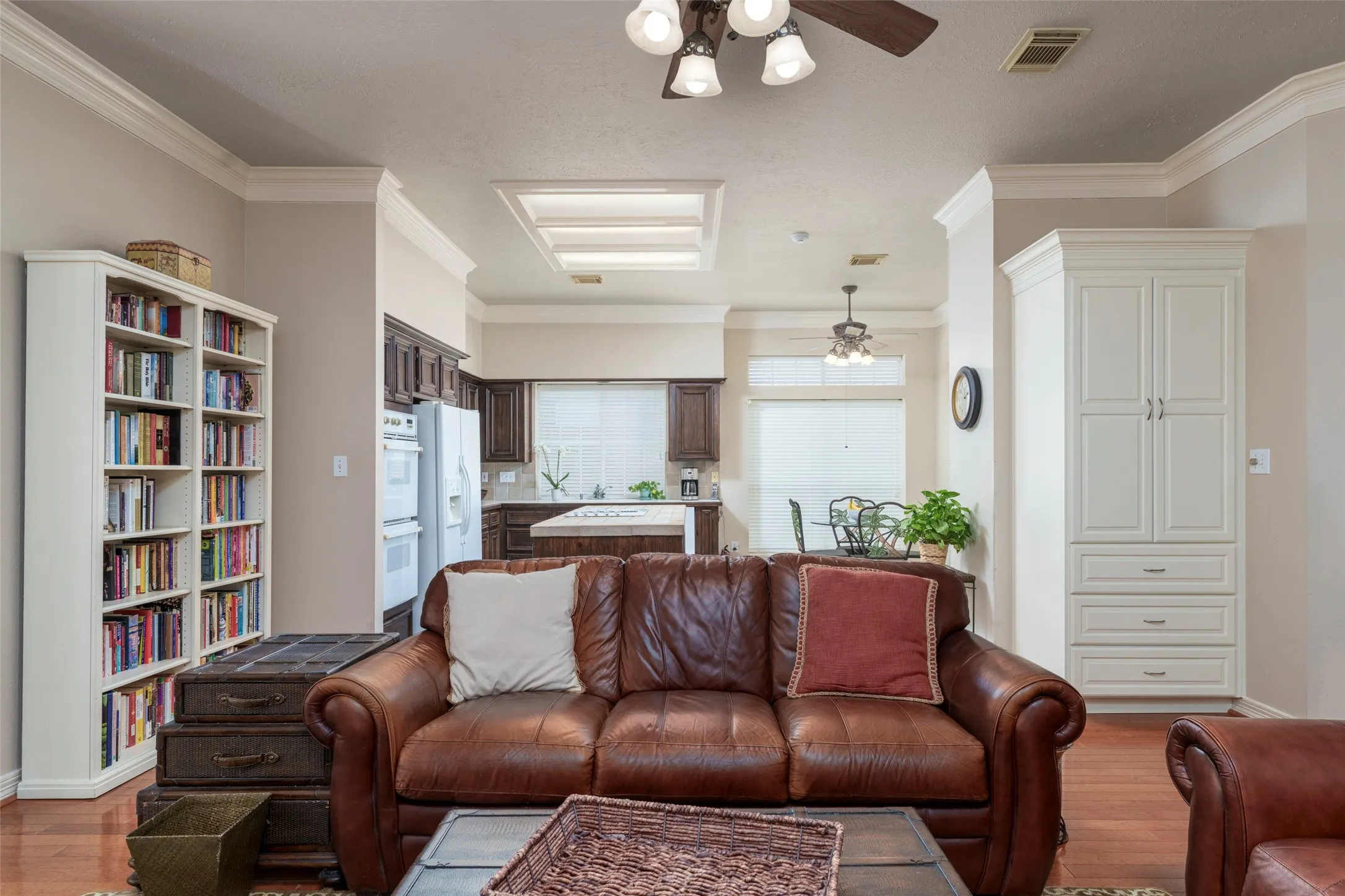 Hardwood-finish flooring, crown molding, built-in cabinetry, ceiling fan with integrated lighting, and recessed ceiling lighting