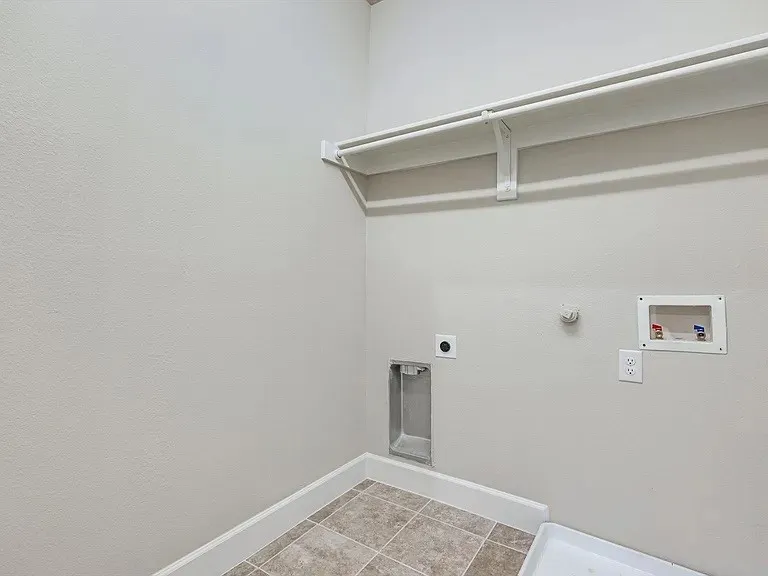Utility area featuring a built-in shelf and hanging rod, tile flooring, and essential appliance hookups