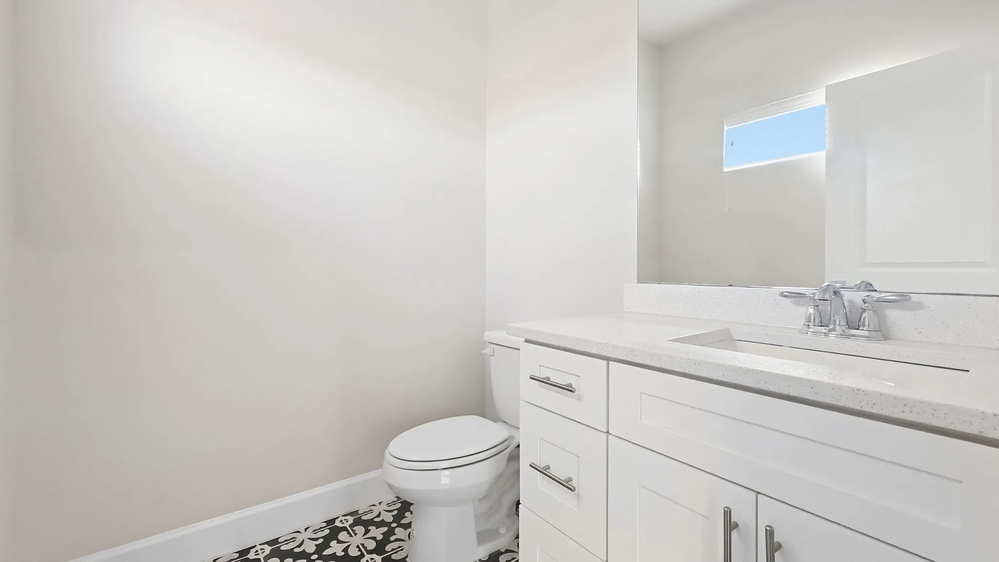 White vanity with chrome hardware, integrated rectangular sink, and light-toned countertop