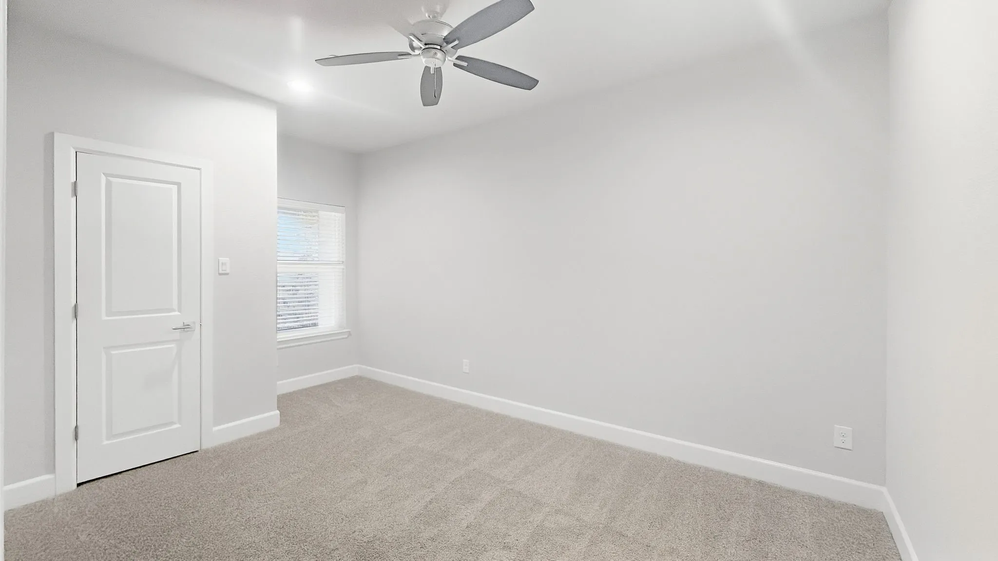 Neutral-toned carpeting, white walls, and a window with blinds
