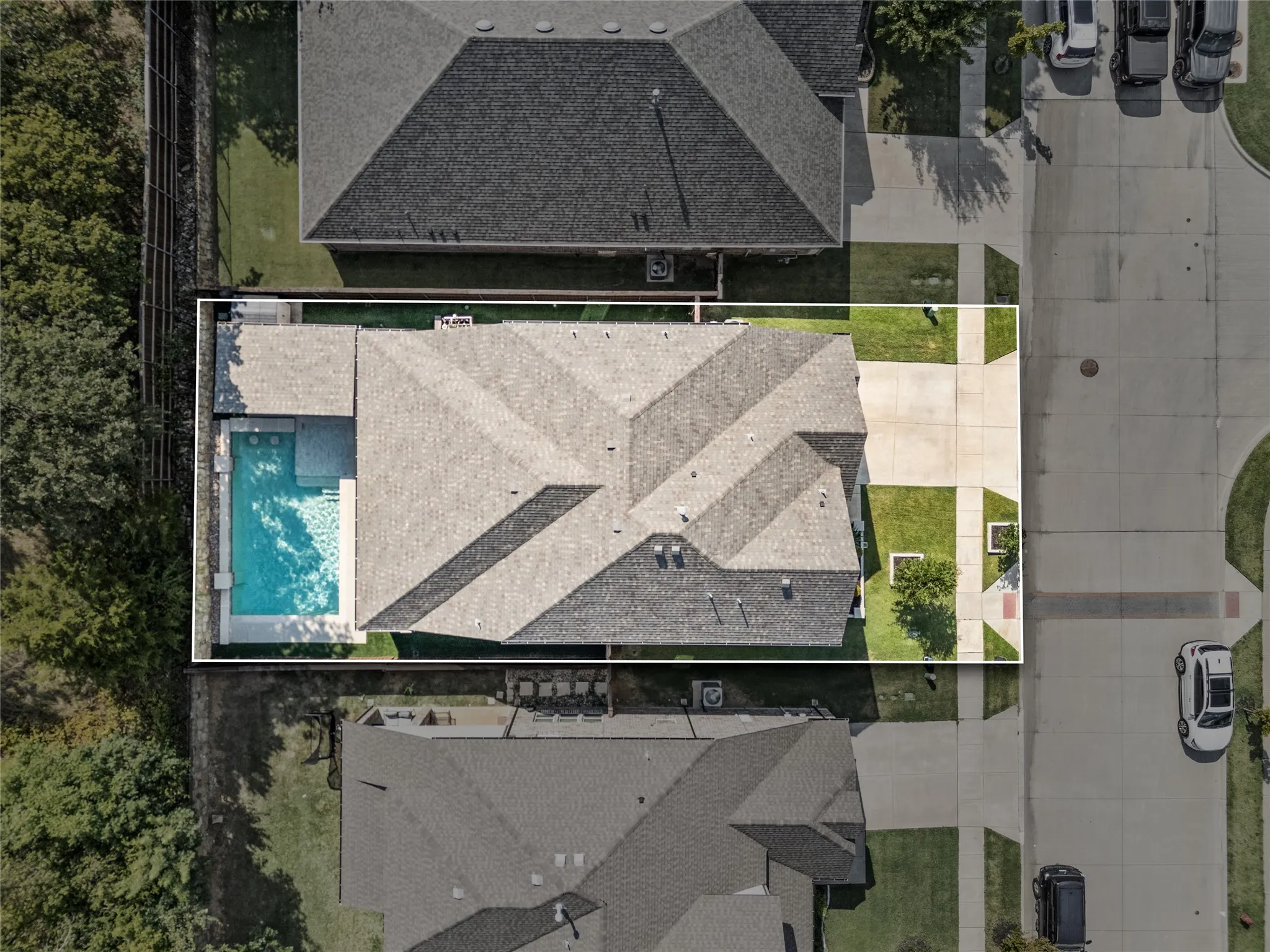 Shingle roof, concrete driveway, manicured lawn, and an in-ground swimming pool