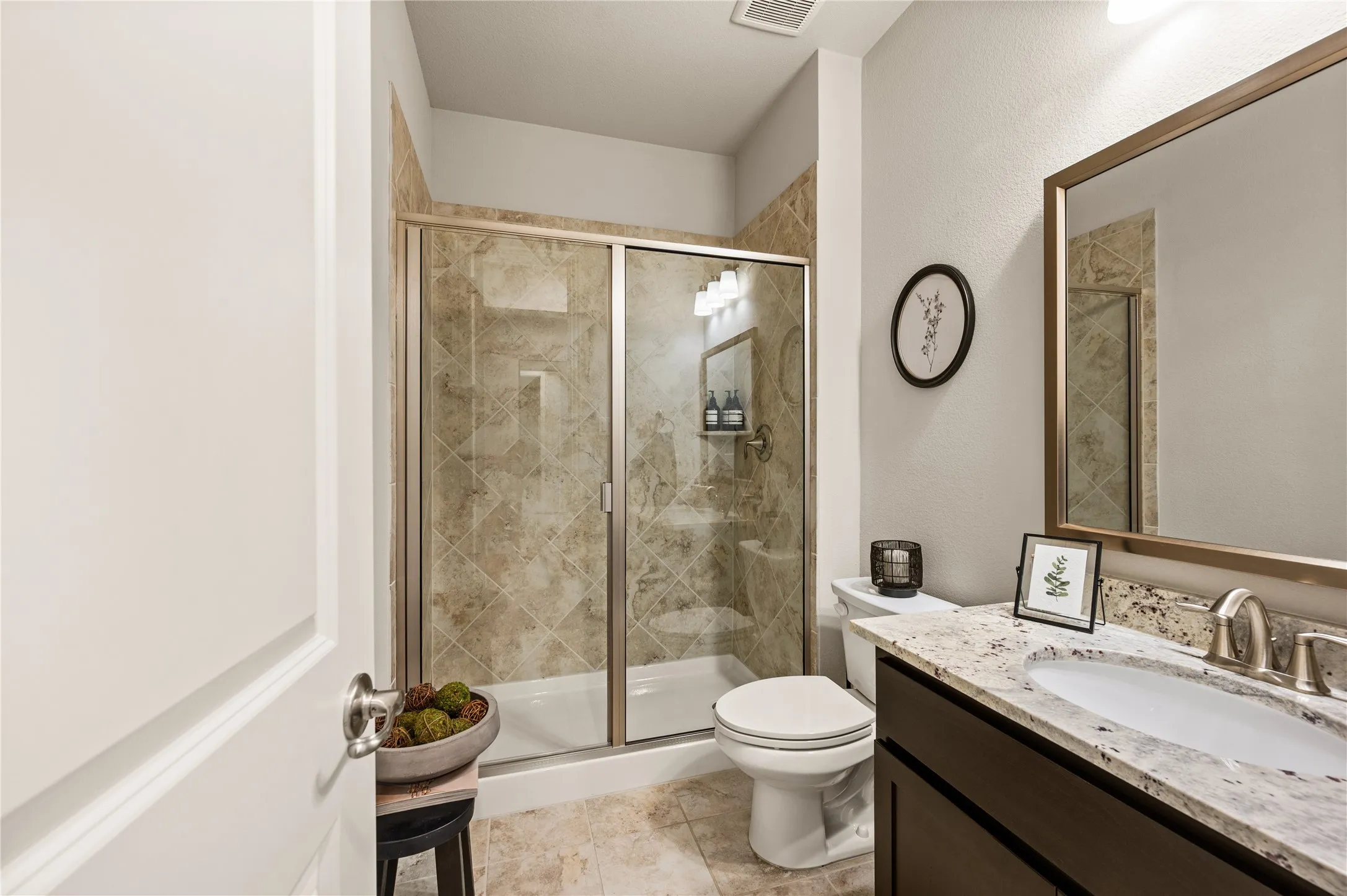 Walk-in shower with glass enclosure and tiled surround, single vanity with light-toned countertop, undermount sink, and brushed nickel faucet