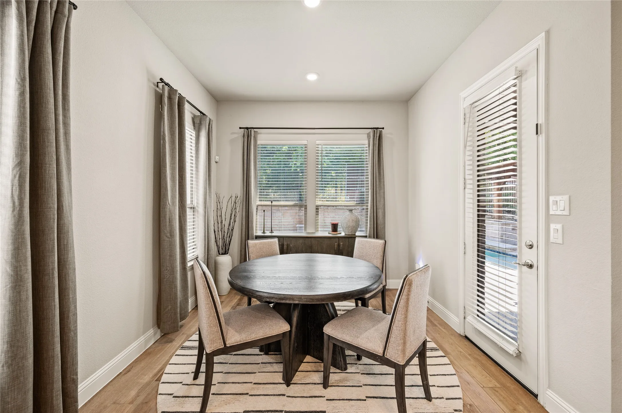 Wood-finish flooring, recessed lighting, and a glass-paneled door with integrated blinds
