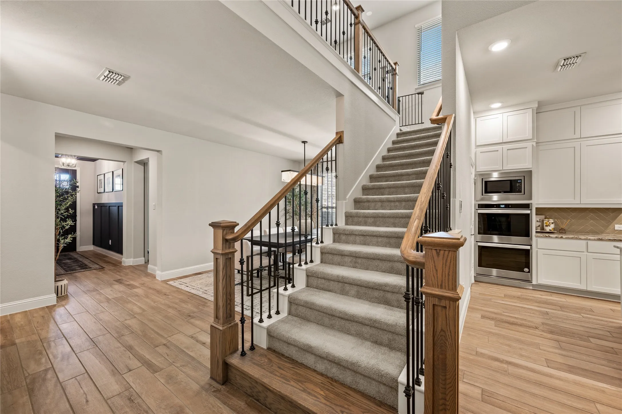 Staircase with wood newel posts, iron balusters, and carpeted treads