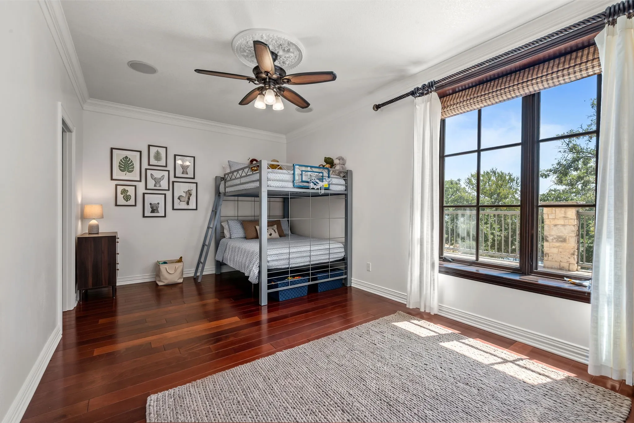 Rich wood-finish flooring, crown molding, and a ceiling fan with decorative medallion