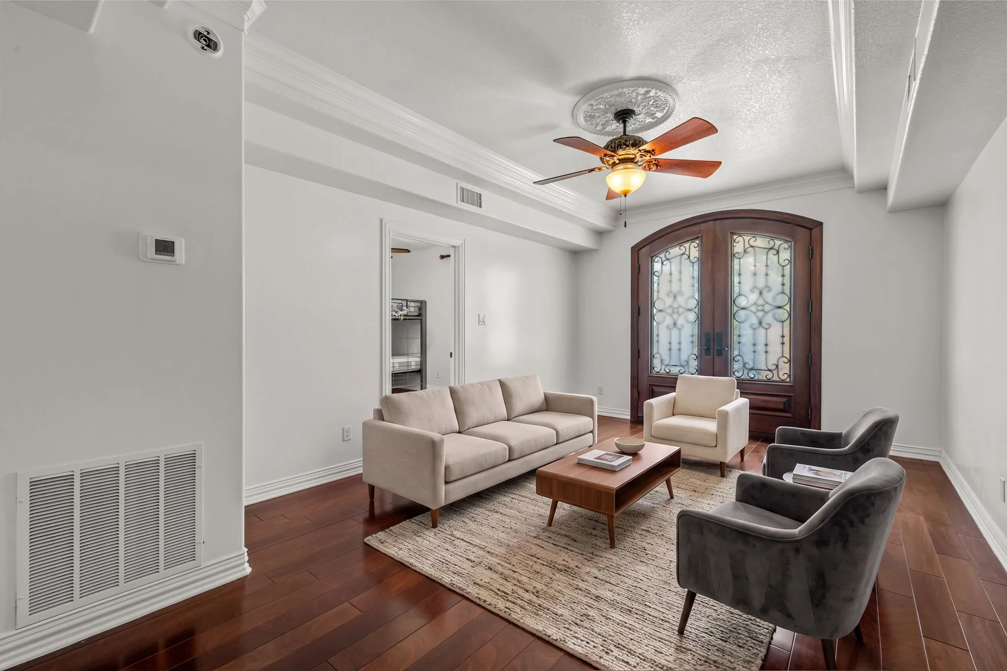 Rich wood-finish flooring, decorative ceiling beams, and a ceiling fan with medallion