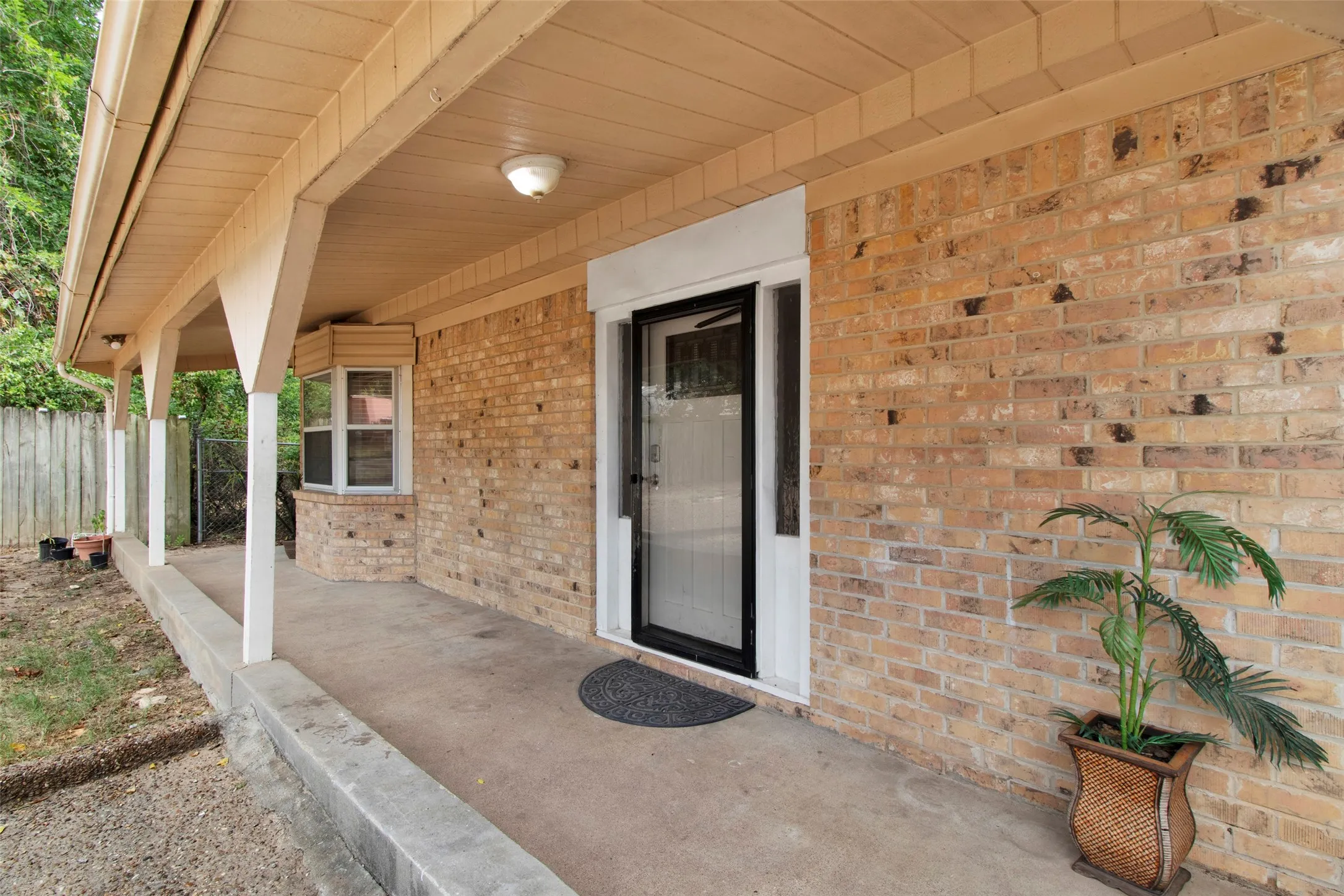 Brick exterior with a covered porch, bay window, and a glass-paneled entry door