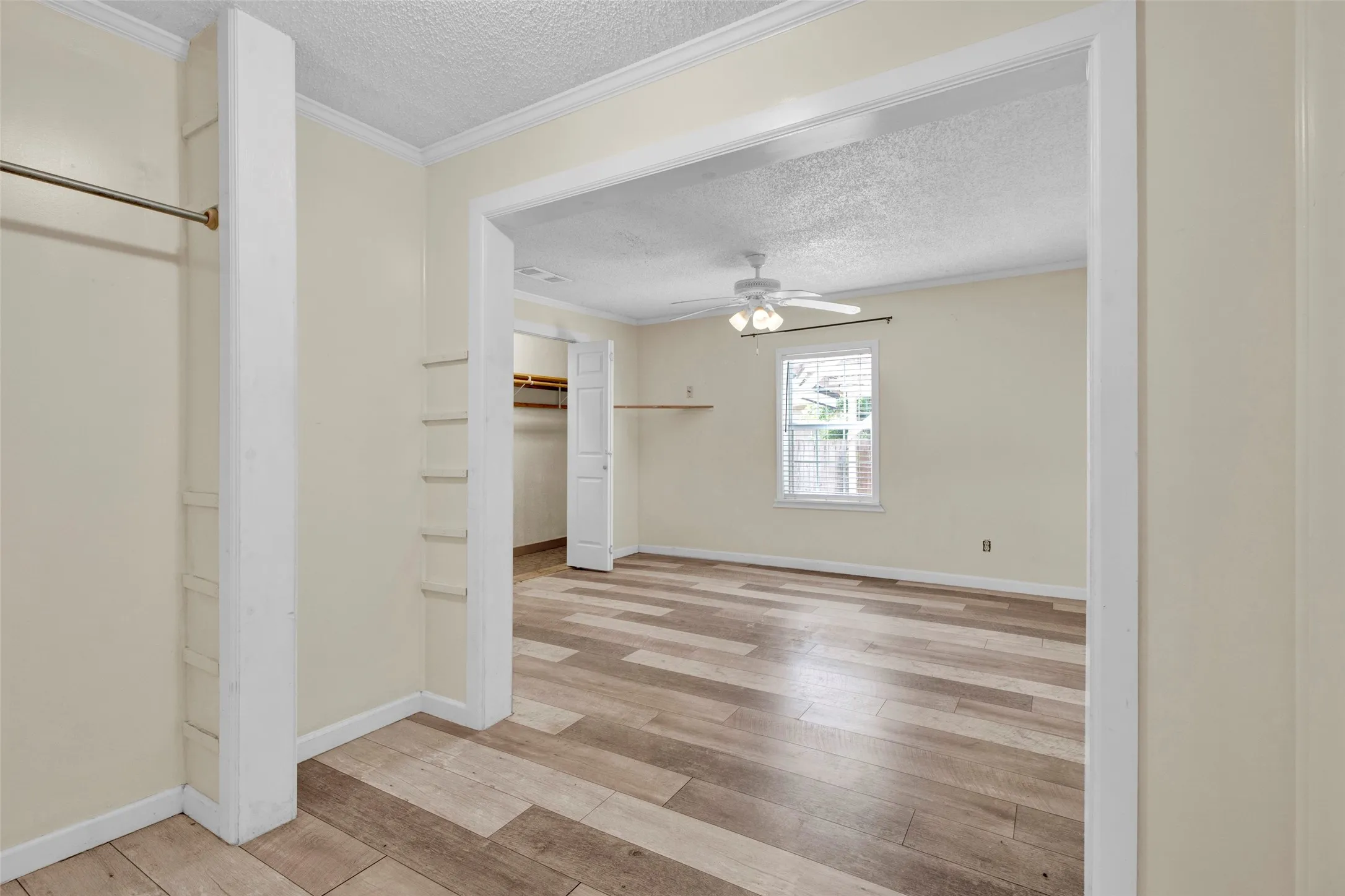 Room with wood-finish flooring, a ceiling fan, and a window with horizontal blinds