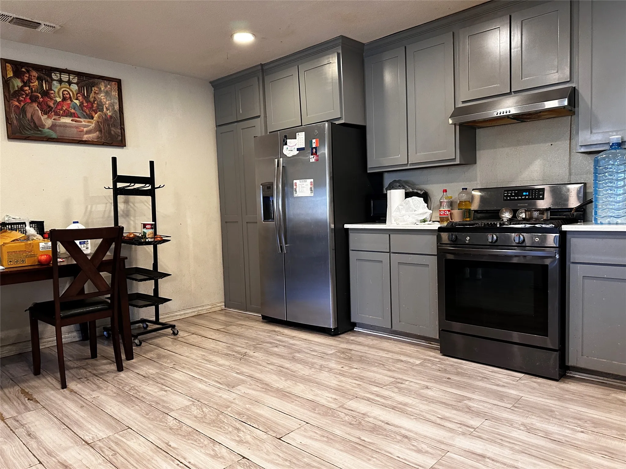 Kitchen featuring wood-finish flooring, gray cabinetry, white countertops, and stainless steel appliances