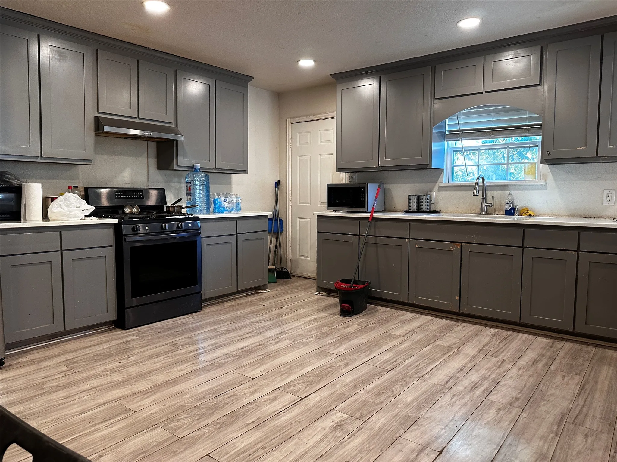 Kitchen featuring wood-finish flooring, recessed lighting, gray cabinetry, a stainless steel range, and a stainless steel sink with a gooseneck faucet