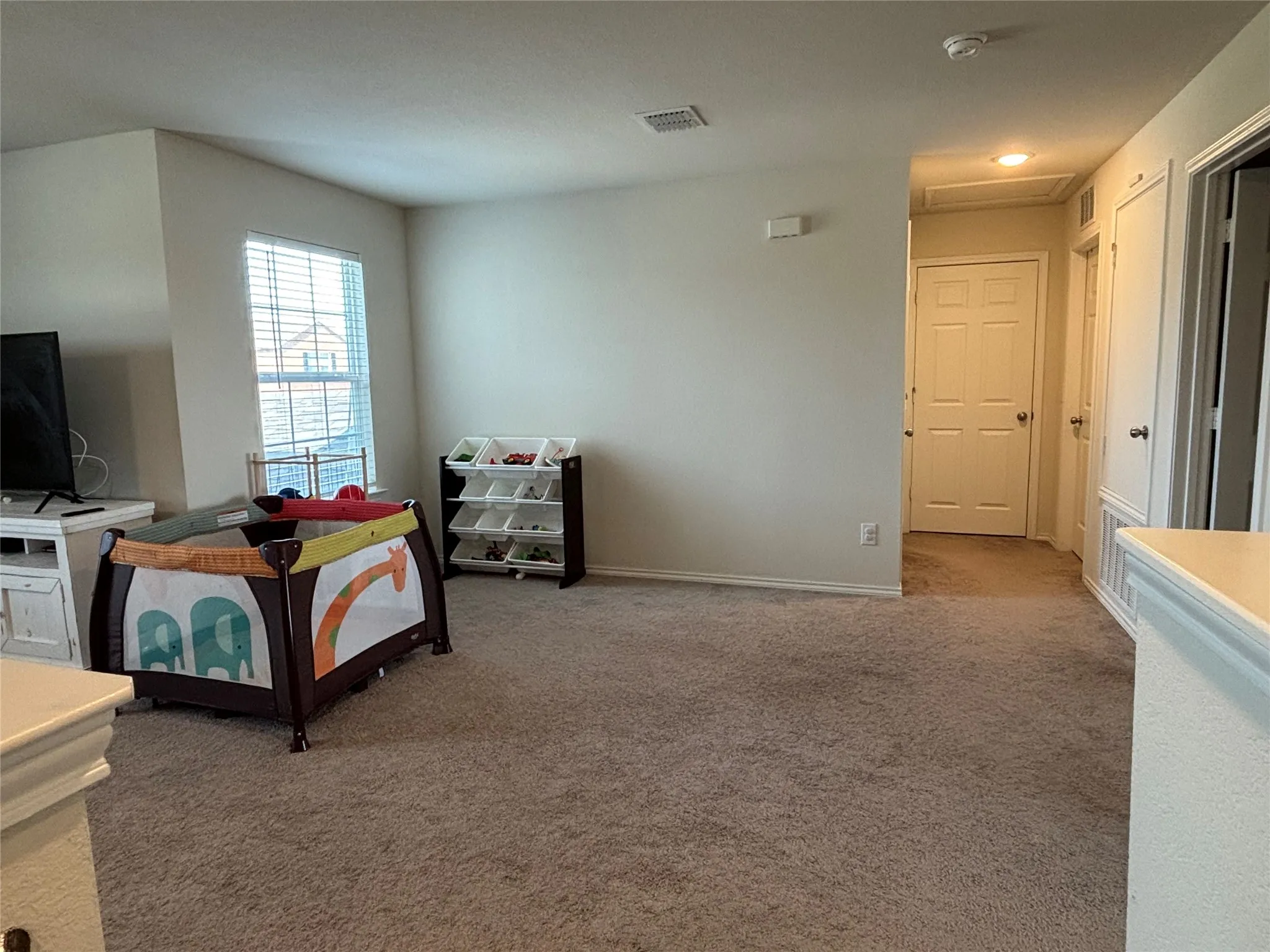 Carpeted flooring throughout, neutral paint finishes and window with horizontal blinds