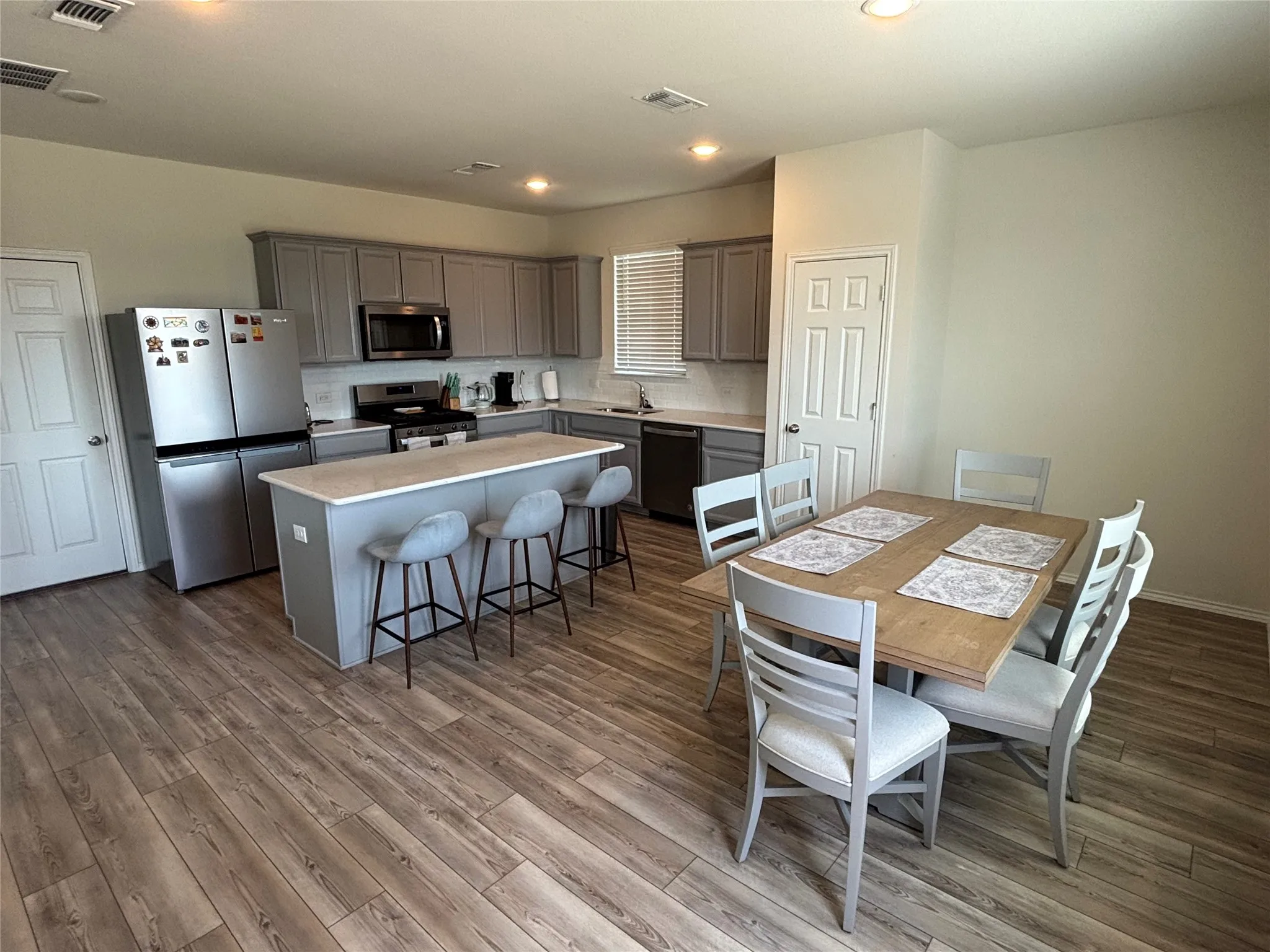 Kitchen featuring wood-finish flooring, an island with countertop seating, and light gray cabinetry