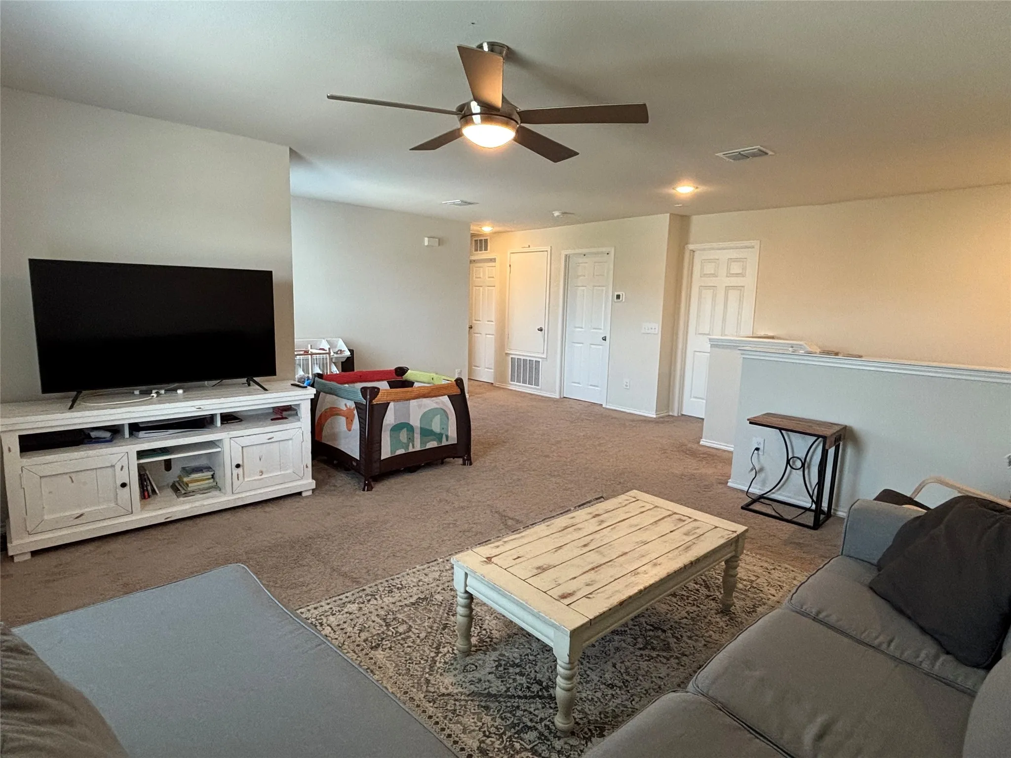 Spacious carpeted room featuring a ceiling fan with integrated lighting, recessed lighting, and multiple doors with panel detailing