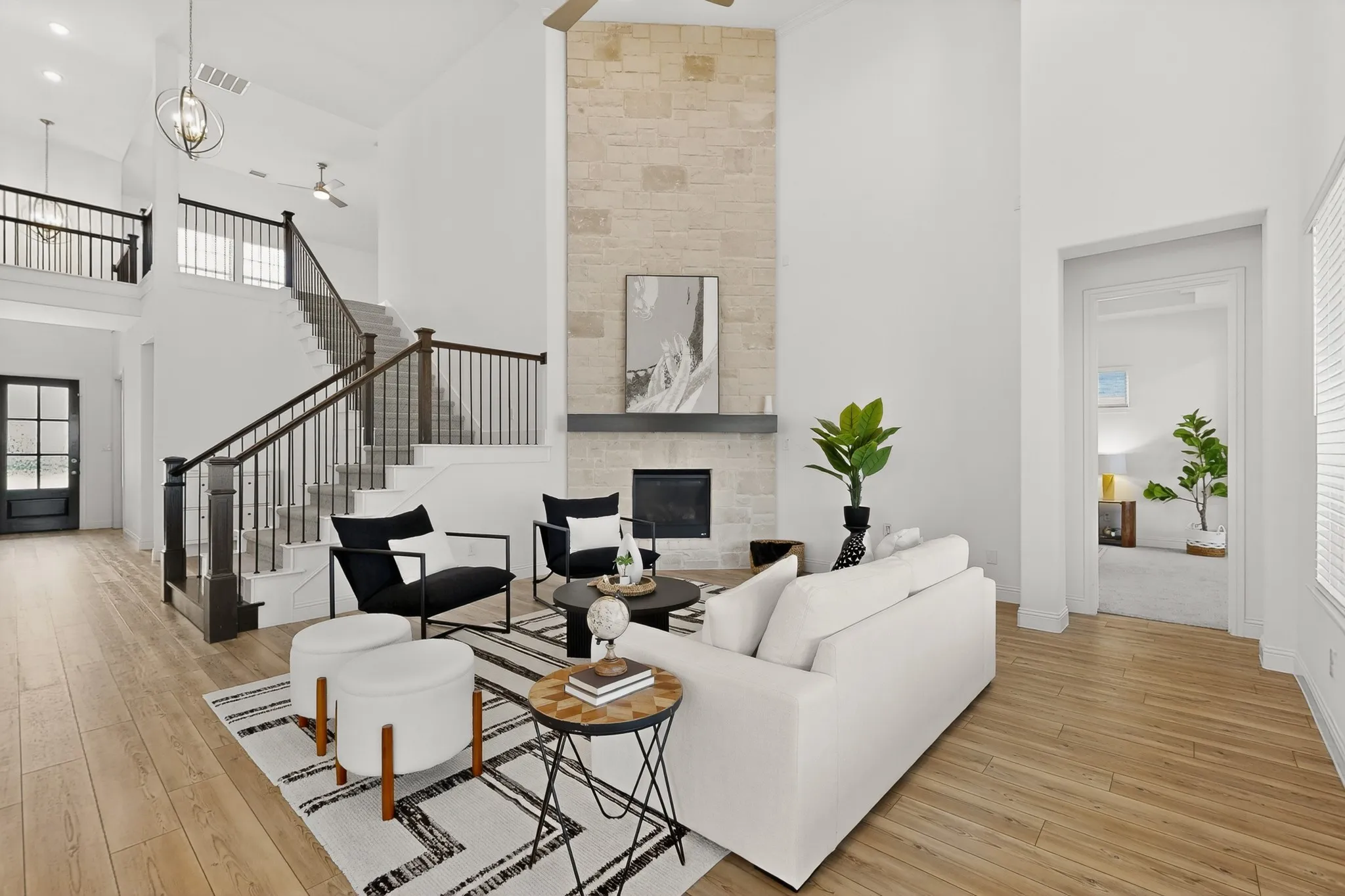 Two-story living area featuring wood-finish flooring, a stone-clad fireplace, and vaulted ceilings