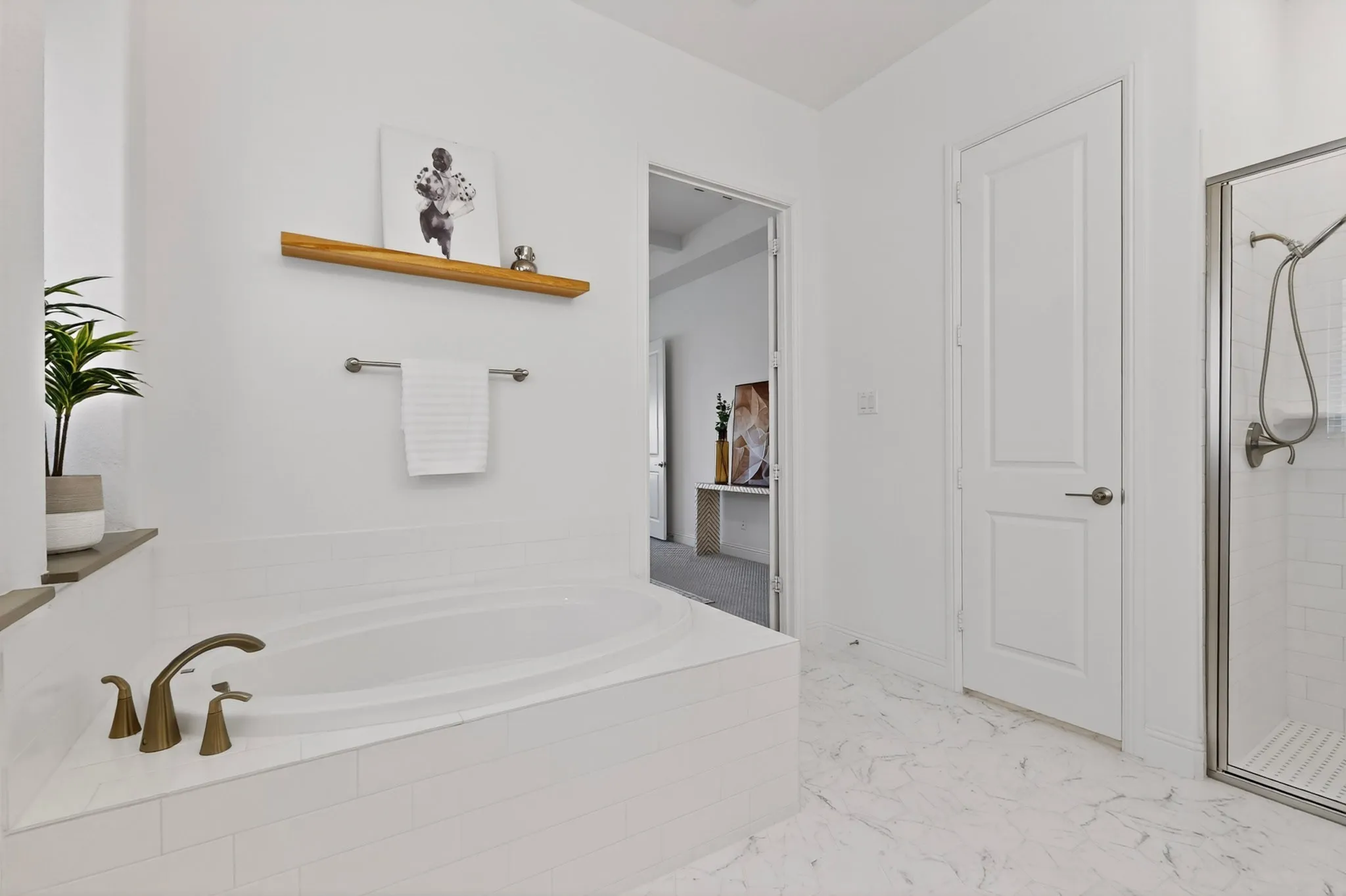 Soaking tub with bronze-finish fixtures, glass-enclosed shower, white tile surround, and patterned flooring