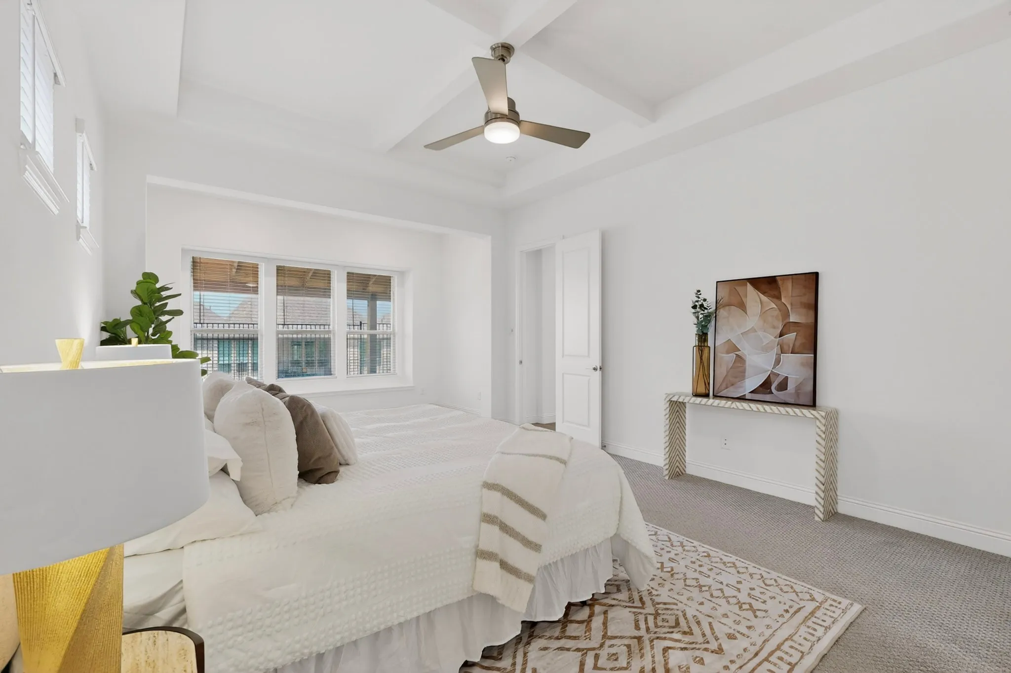 Recessed ceiling with an integrated ceiling fan, multiple window exposures, wall-to-wall carpeting, and a white interior door