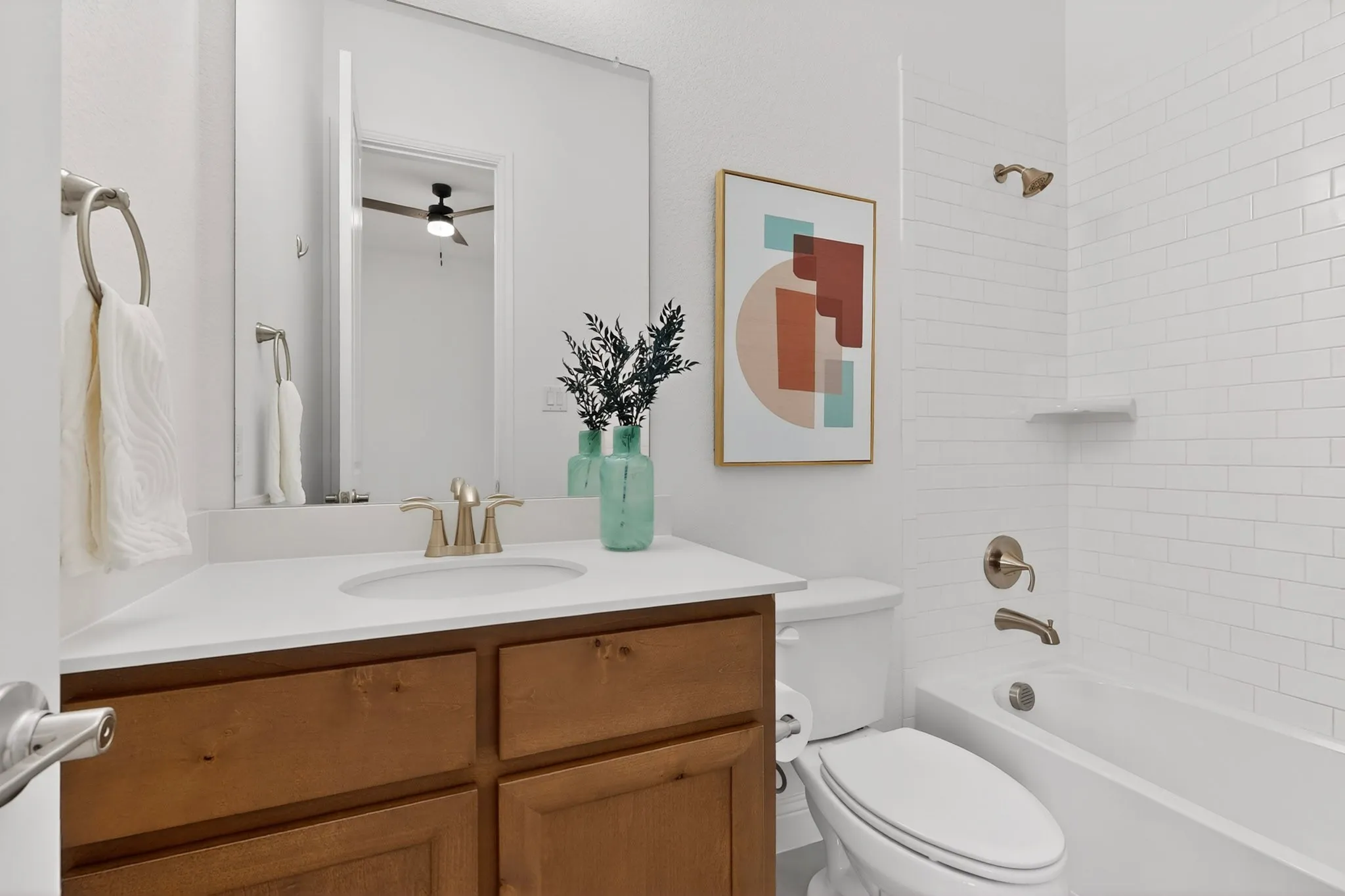Wood-finish vanity with a single basin sink, white countertop, and gold-tone faucet