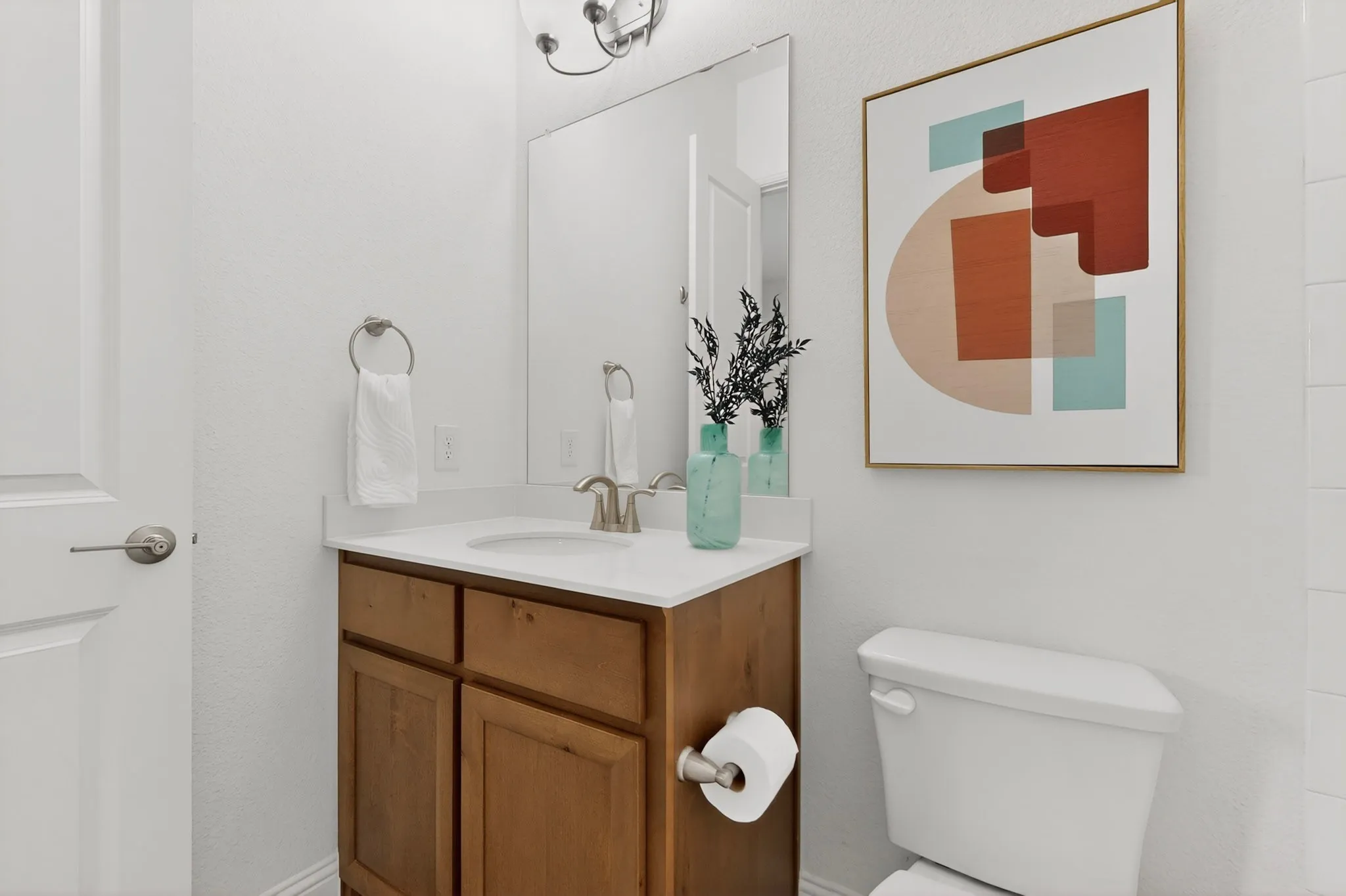 White vanity with a single basin, brushed nickel faucet, and wood-finish cabinetry, complemented by a wall-mounted mirror