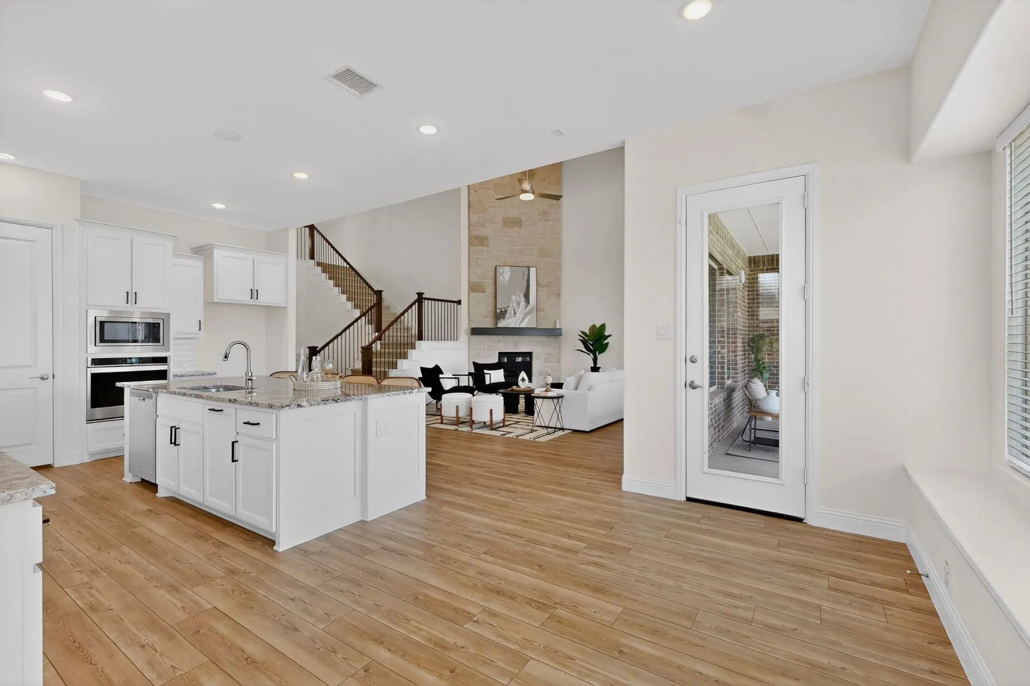 Kitchen featuring an island with a sink, white cabinetry, integrated oven, and microwave