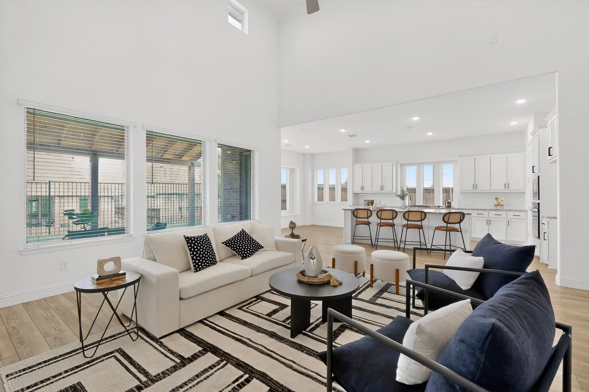 Vaulted ceiling, wood-finish flooring, recessed lighting, white cabinetry, and a kitchen island with built-in seating
