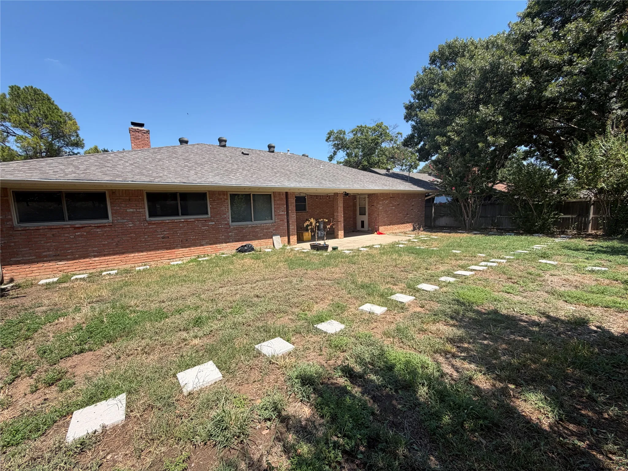 Brick exterior with a covered patio and a stepping stone pathway