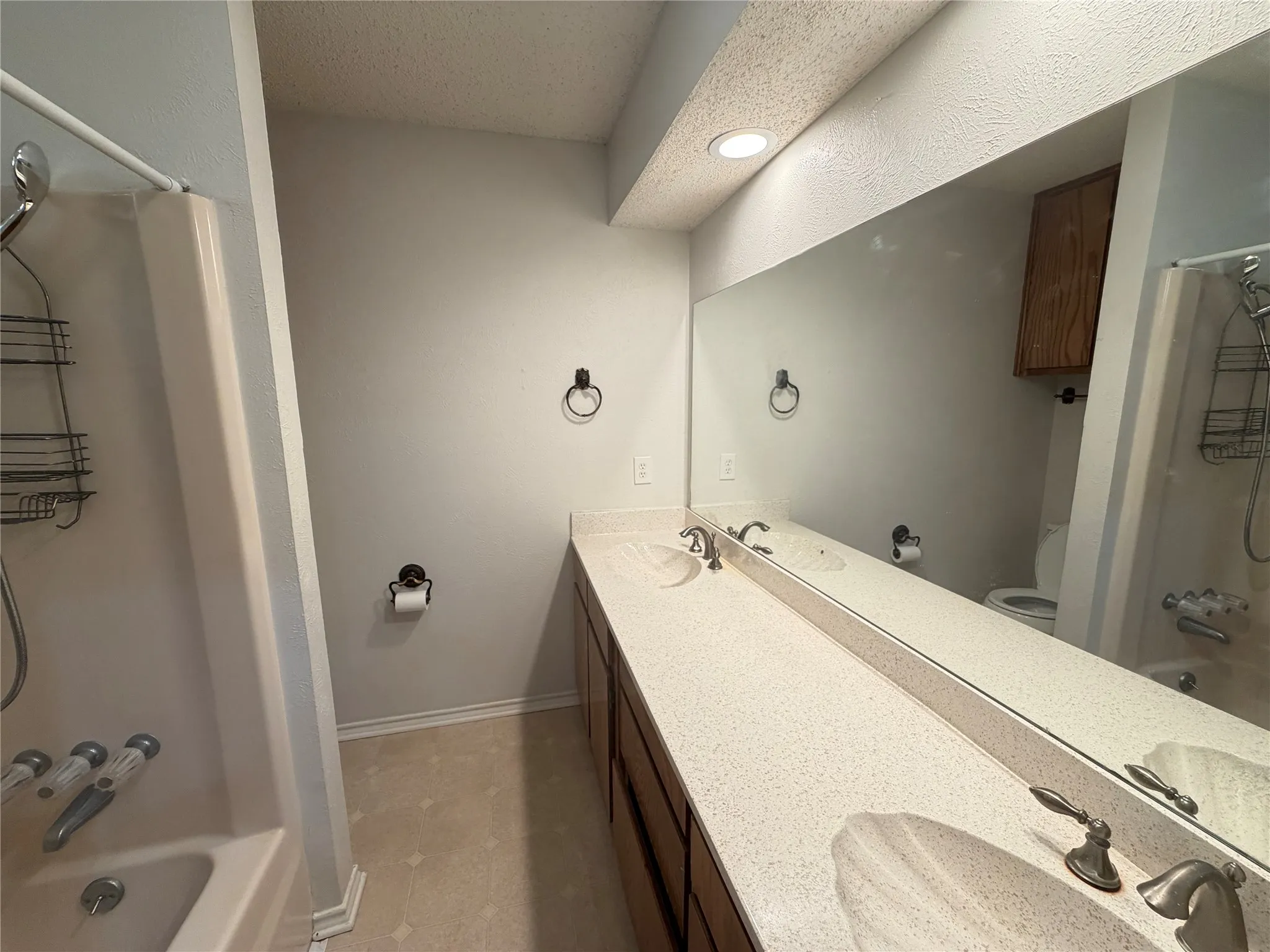 Dual vanity with integrated sinks, expansive wall-mounted mirror, and wood-finish cabinetry