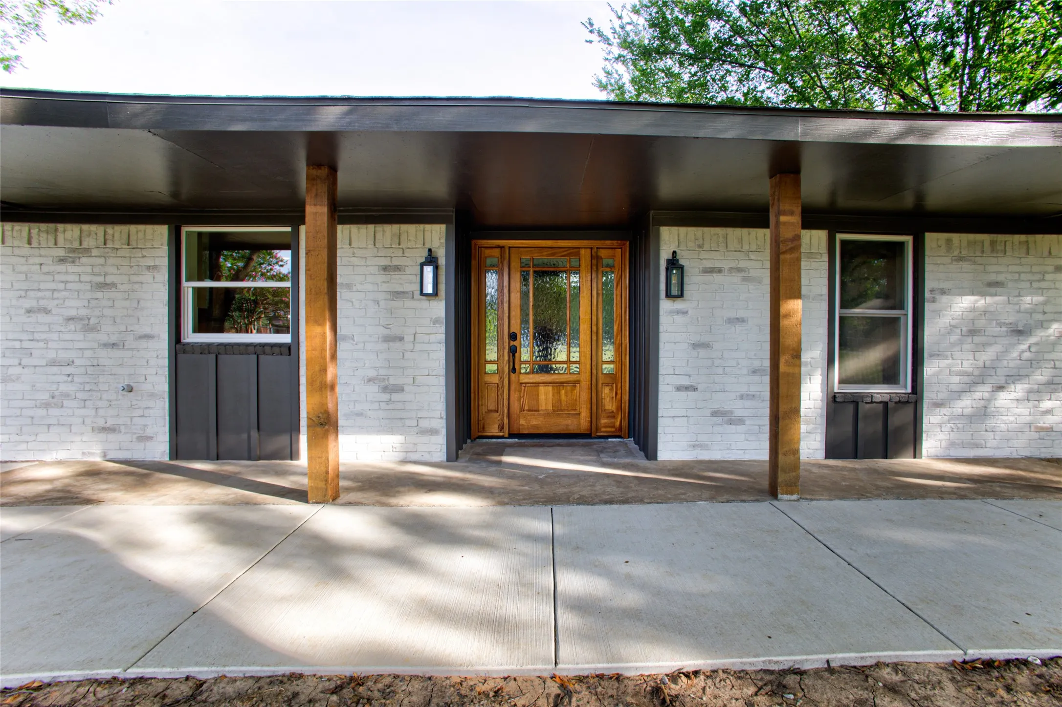 New Grand Solid Wood Front Door wTwo Side Lights & Exterior Wood Stained Accents To Match. And Wide Concrete Wrap Sidewalk From Carport