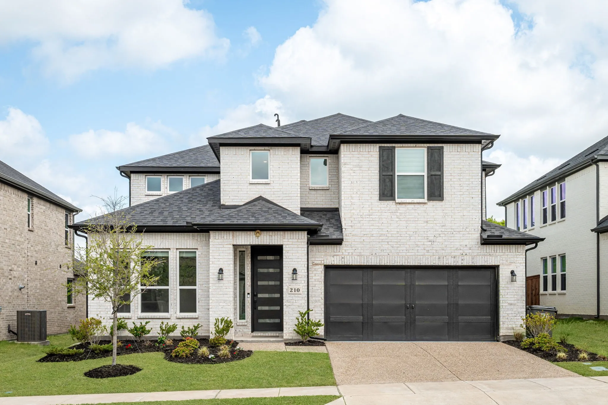 View of front of home featuring an attached garage, driveway, roof with shingles, and brick siding