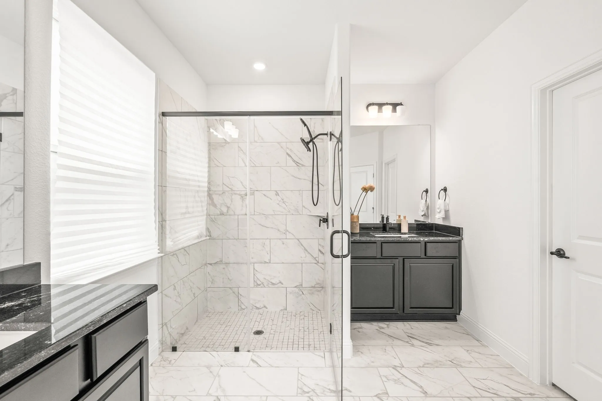 Bathroom with two vanities, a stall shower, and light marble finish floors