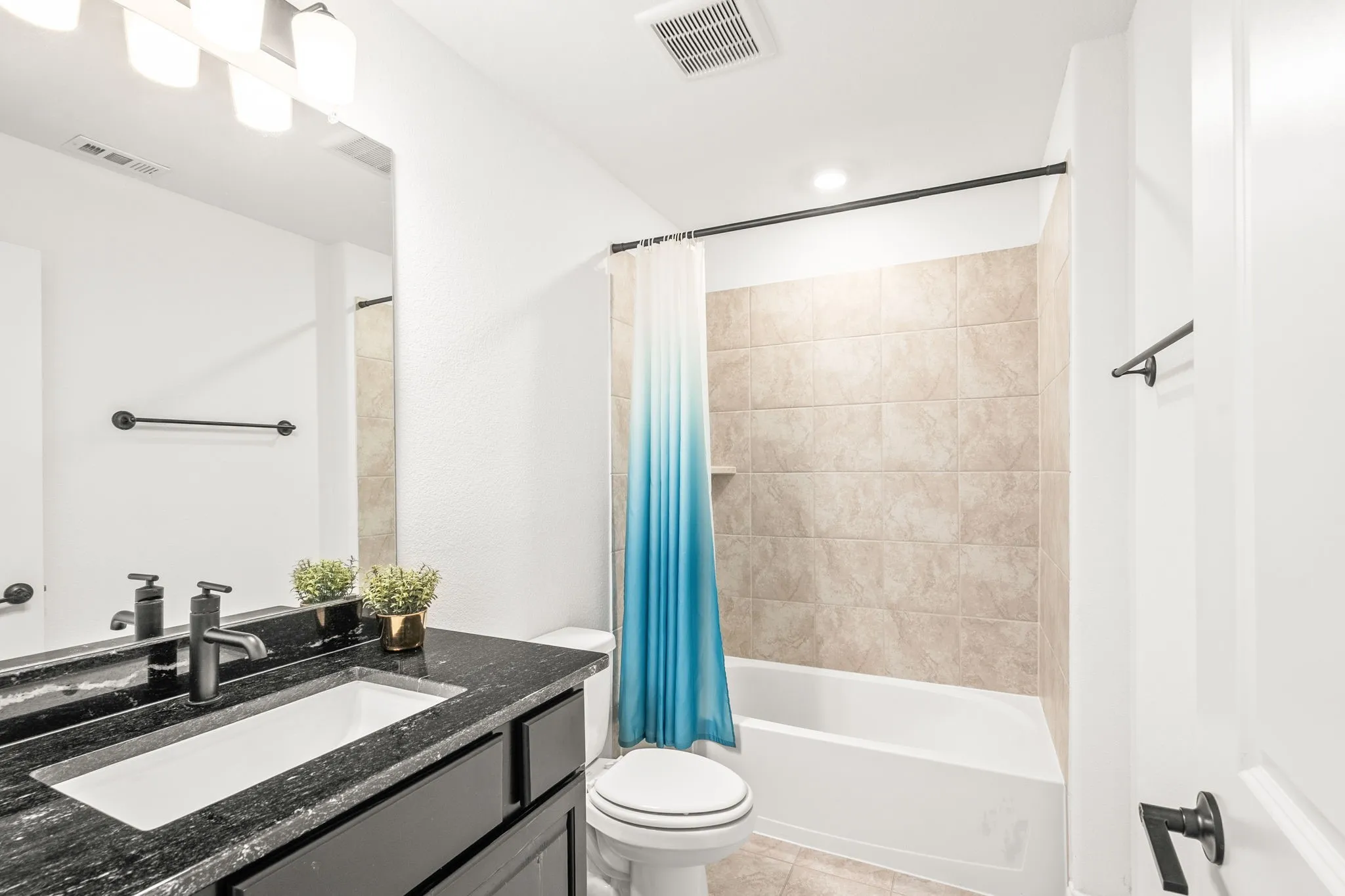 Full bathroom featuring vanity, shower / bath combo with shower curtain, and light tile patterned floors
