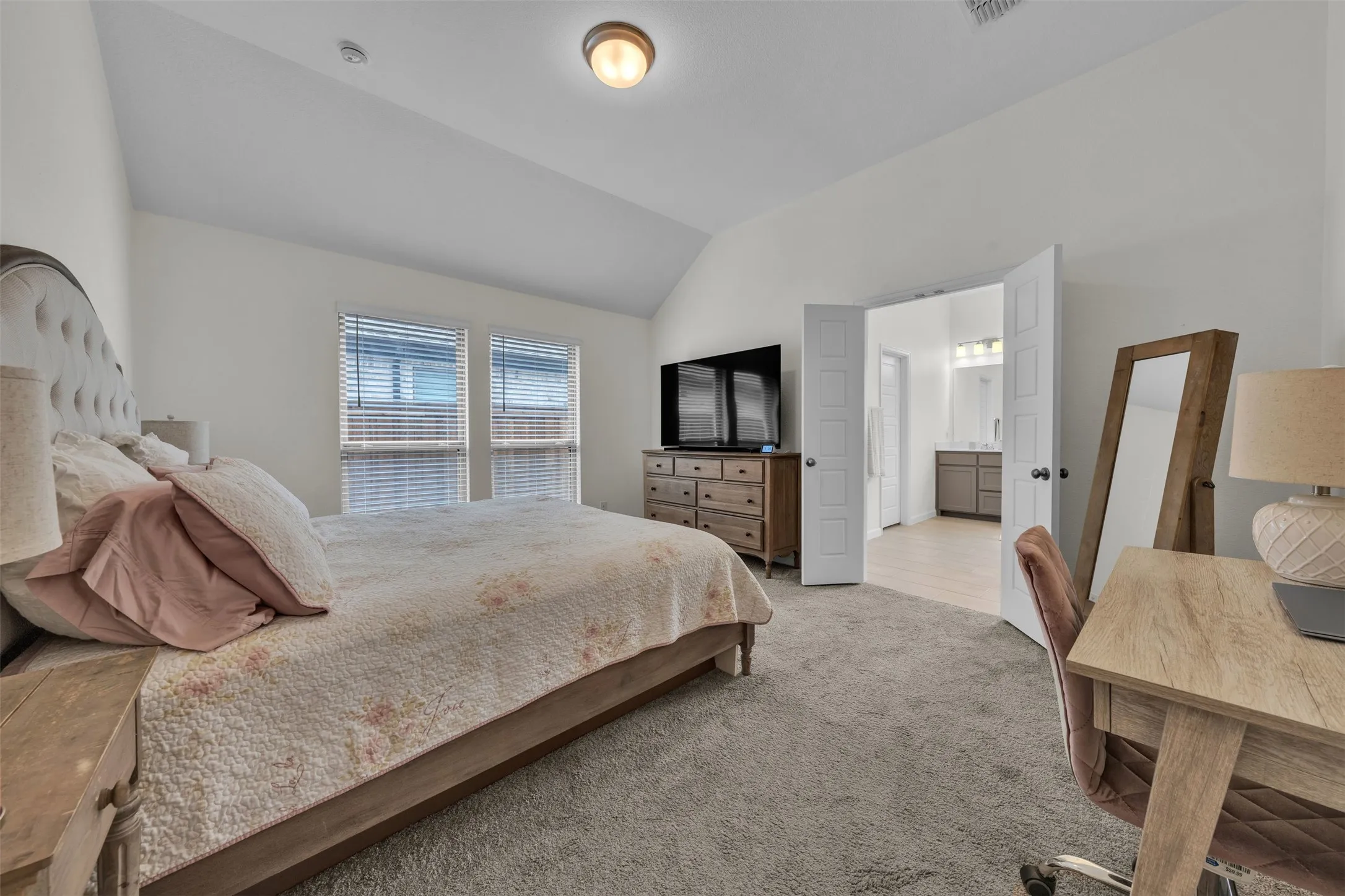 Vaulted ceilings, twin windows with blinds, carpeted flooring, and a pair of panel doors