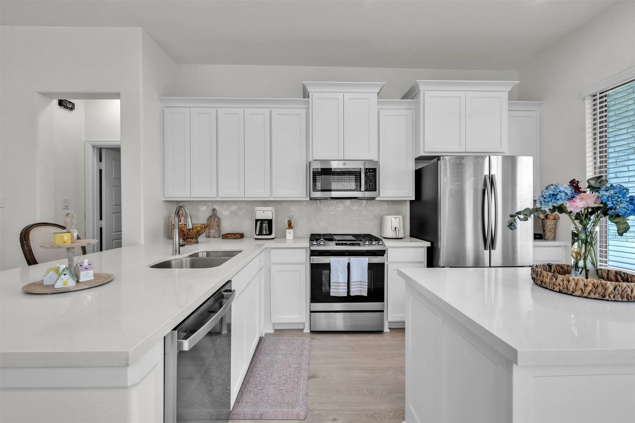 Kitchen featuring white cabinetry, stainless steel appliances, white countertops, and wood-finish flooring