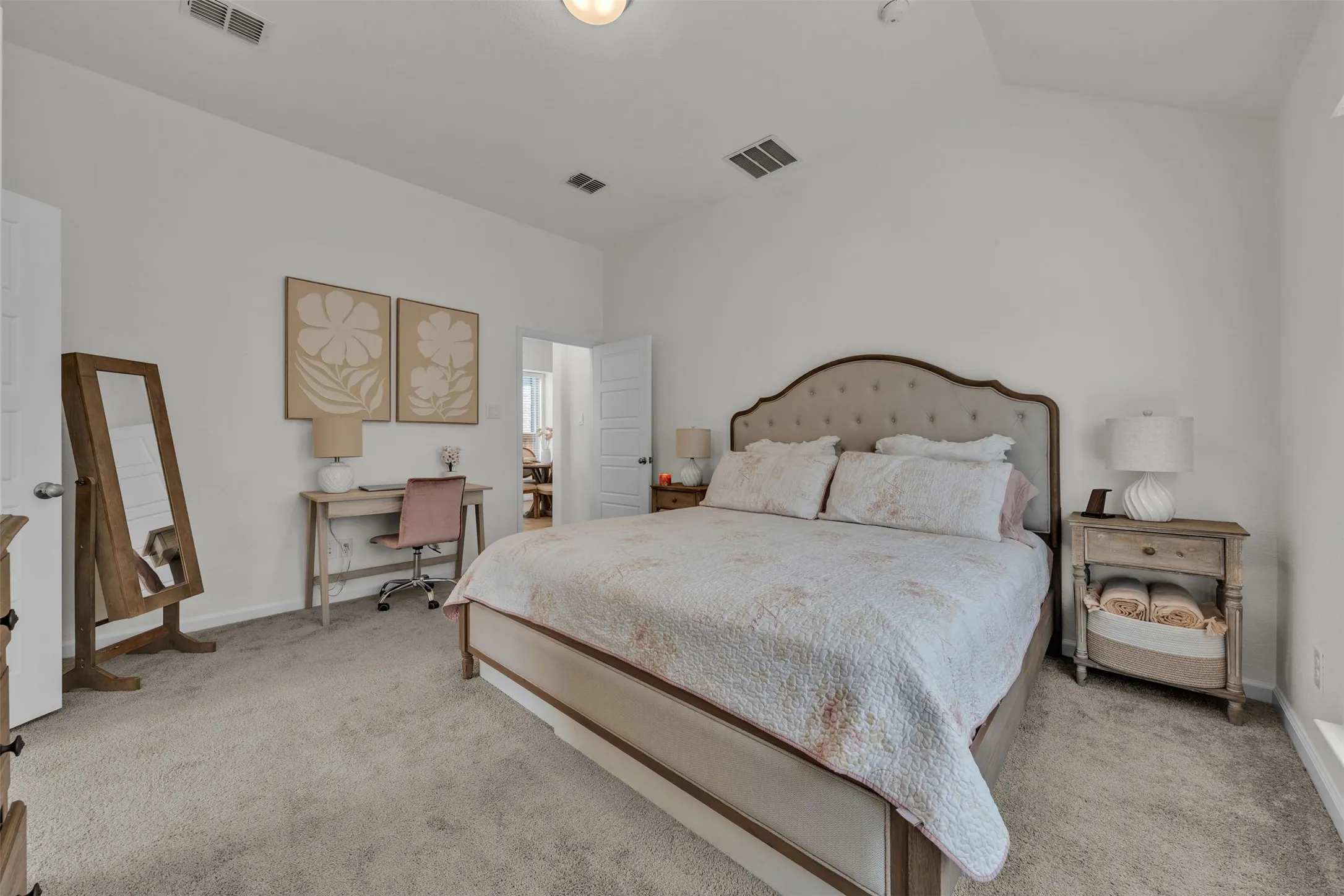 White painted walls, vaulted ceiling, and light-toned carpet flooring