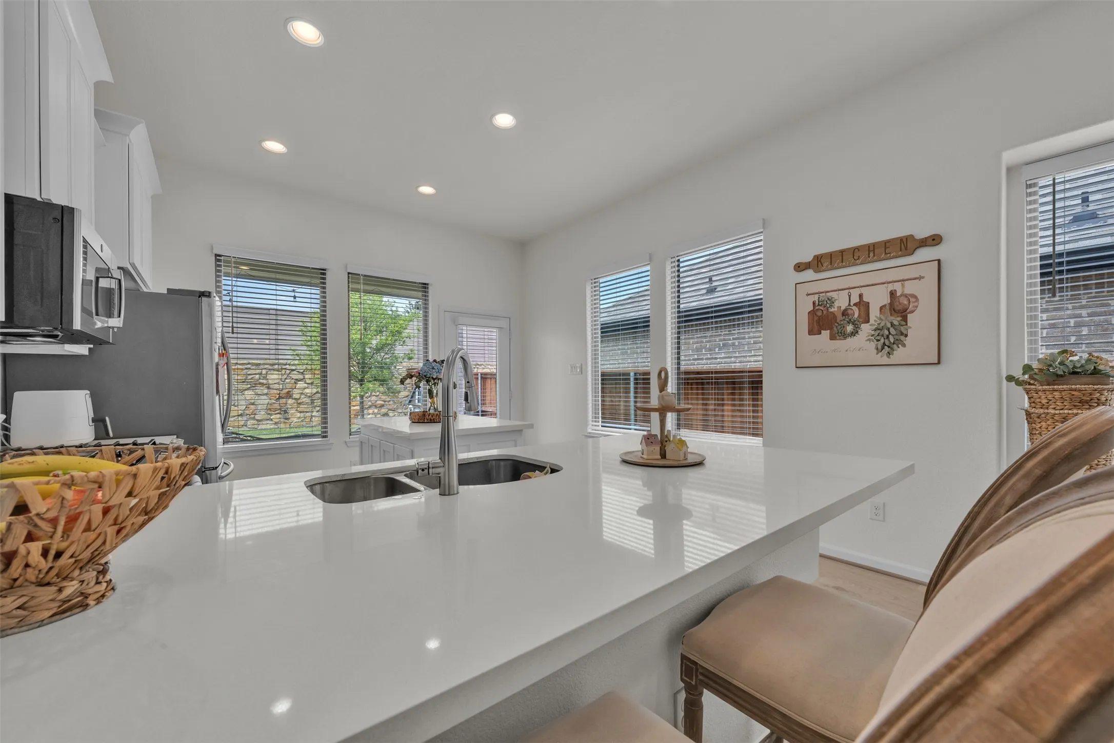 White cabinetry and ceiling-mounted recessed lighting complement the light-toned countertops
