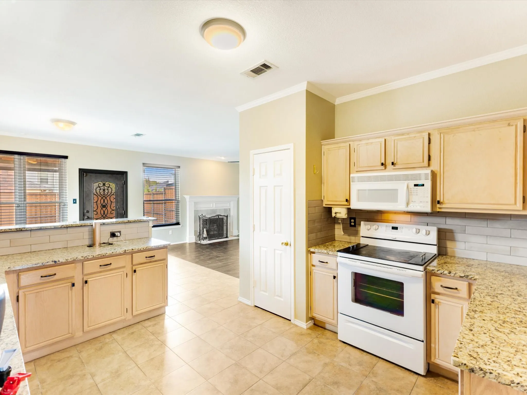 Kitchen featuring light wood-finish cabinetry, granite-style countertops, and a subway tile backsplash