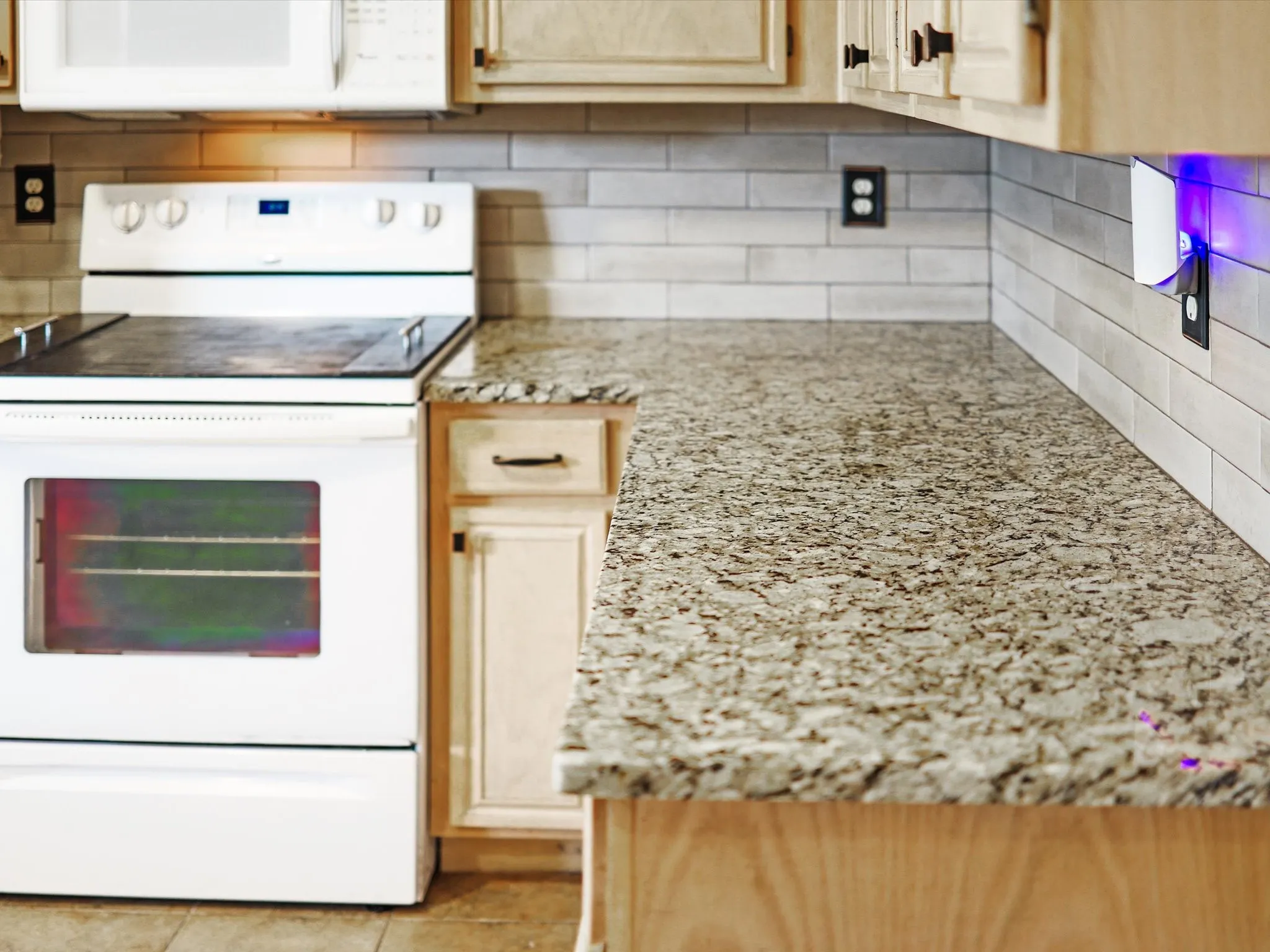 Granite-style countertops, wood-finish cabinetry, tile backsplash, and a white electric range