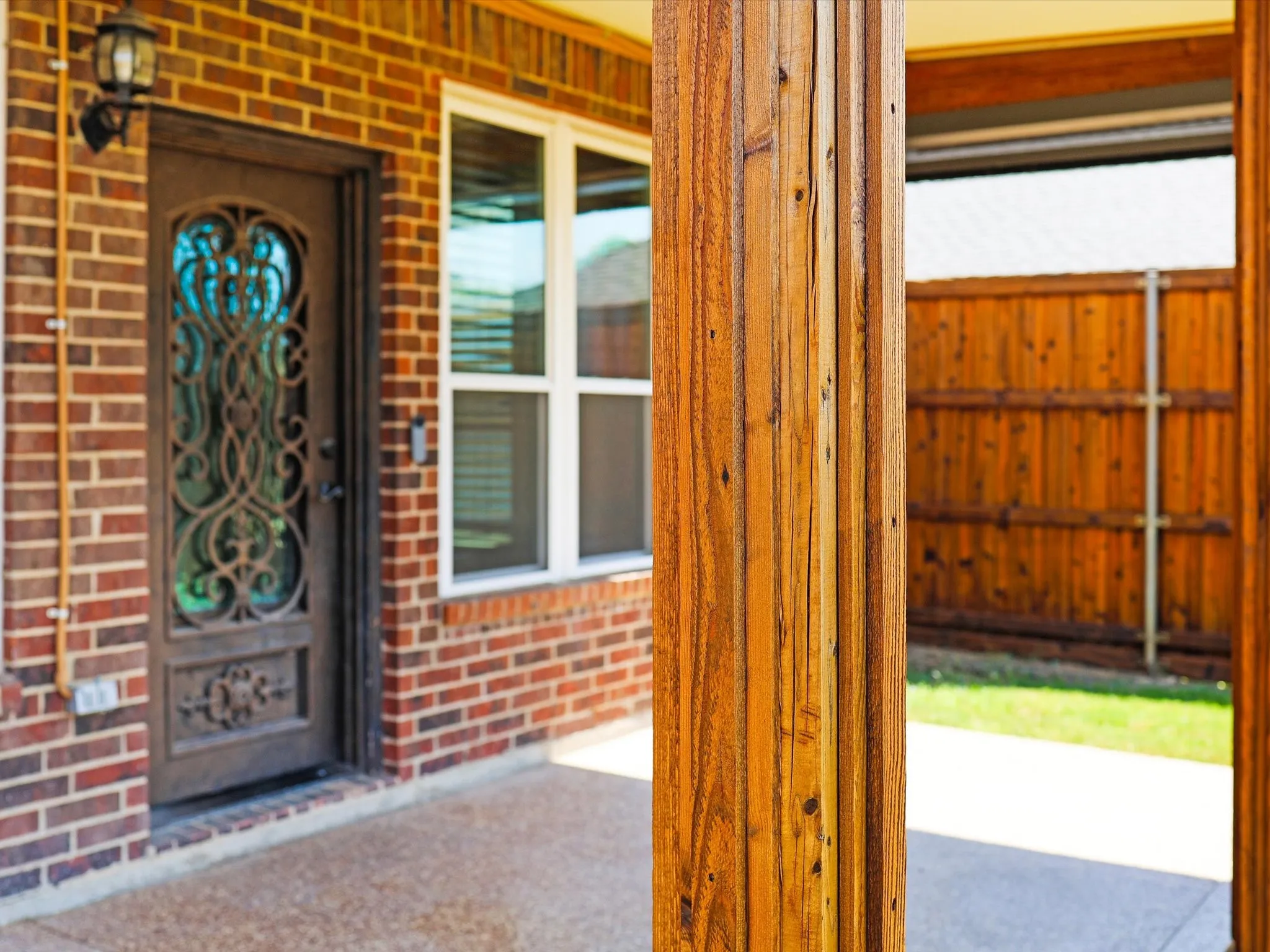 Brick exterior with a decorative iron and glass front door, complemented by a large white-framed window