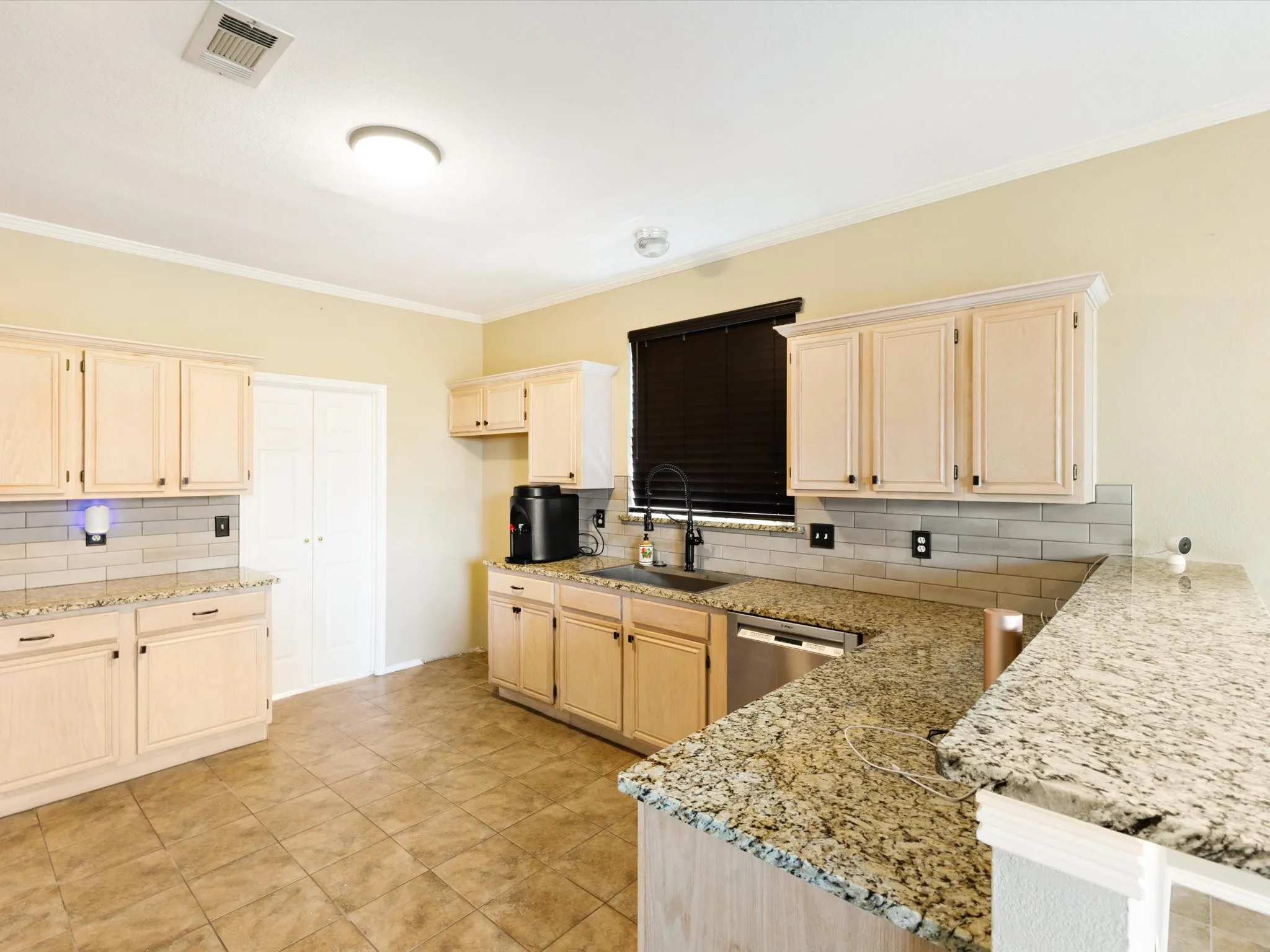 Kitchen featuring light wood cabinetry, granite countertops, subway tile backsplash, and tile flooring