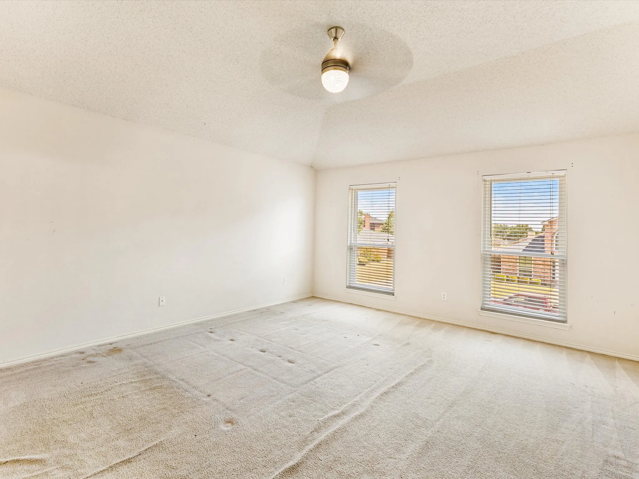 Spacious room with dual windows, textured ceiling, and a central ceiling light fixture