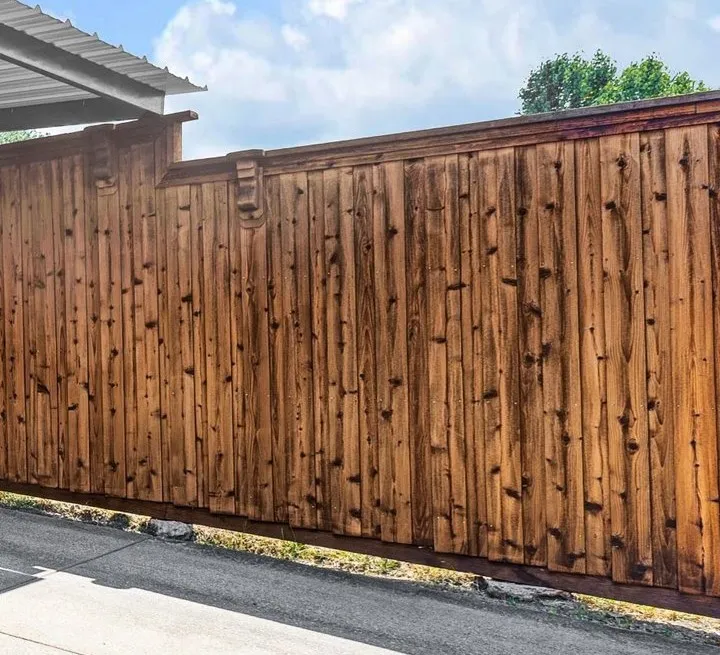 Wood panel fencing with decorative finials and a top rail accent