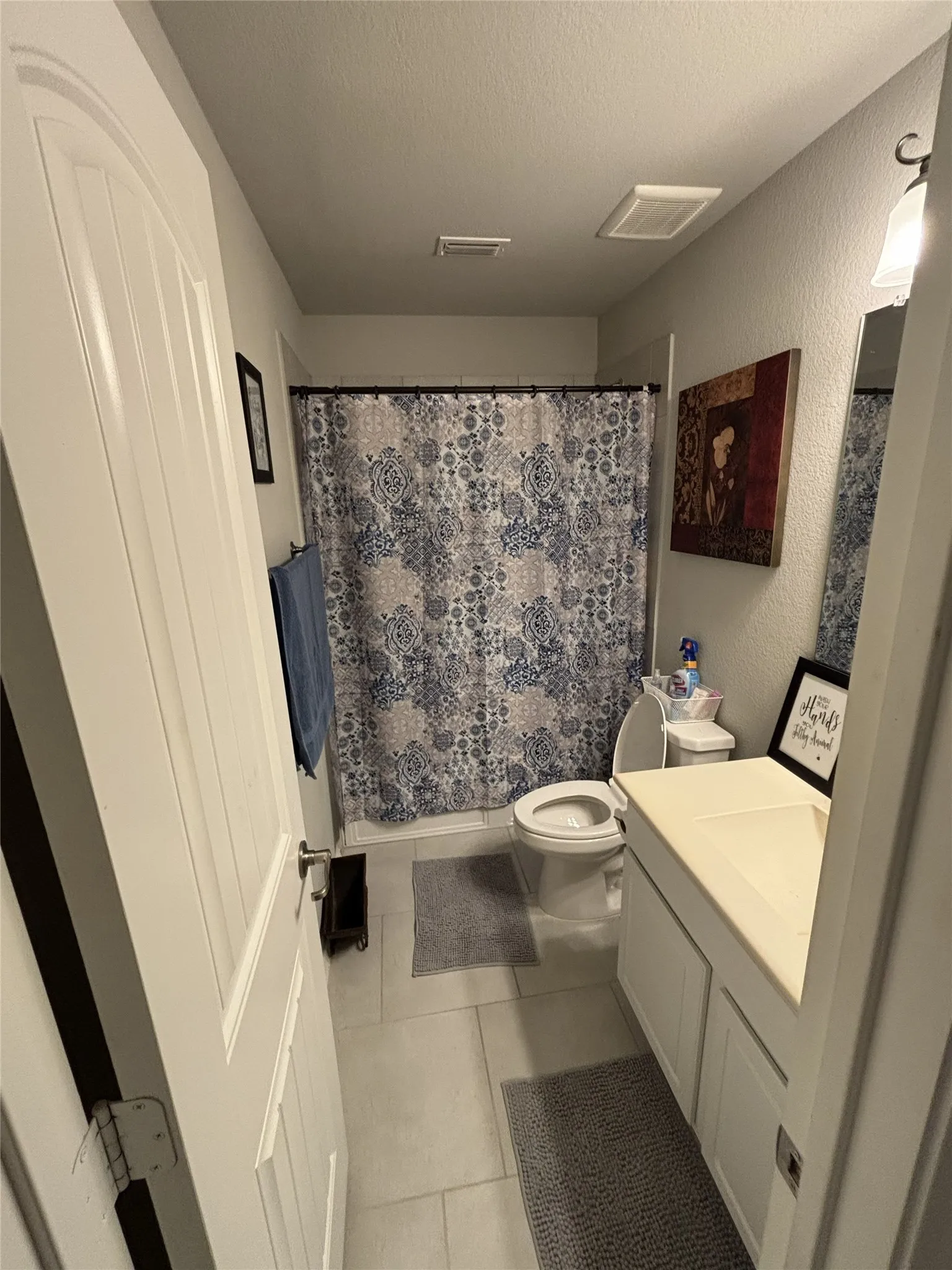 White vanity with integrated sink, white toilet, and tiled flooring