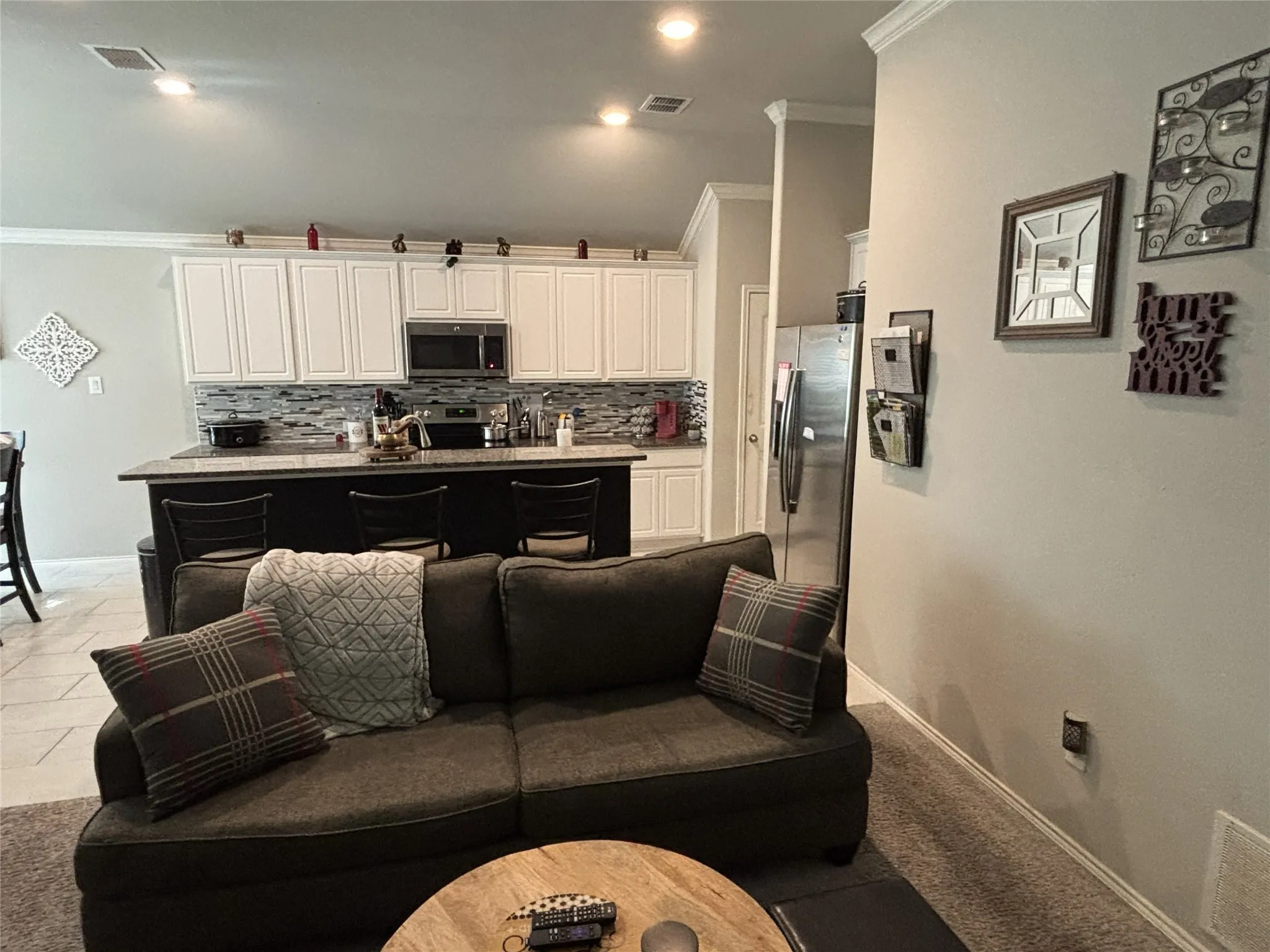 Kitchen featuring white upper cabinetry, stainless steel microwave, and mosaic tile backsplash