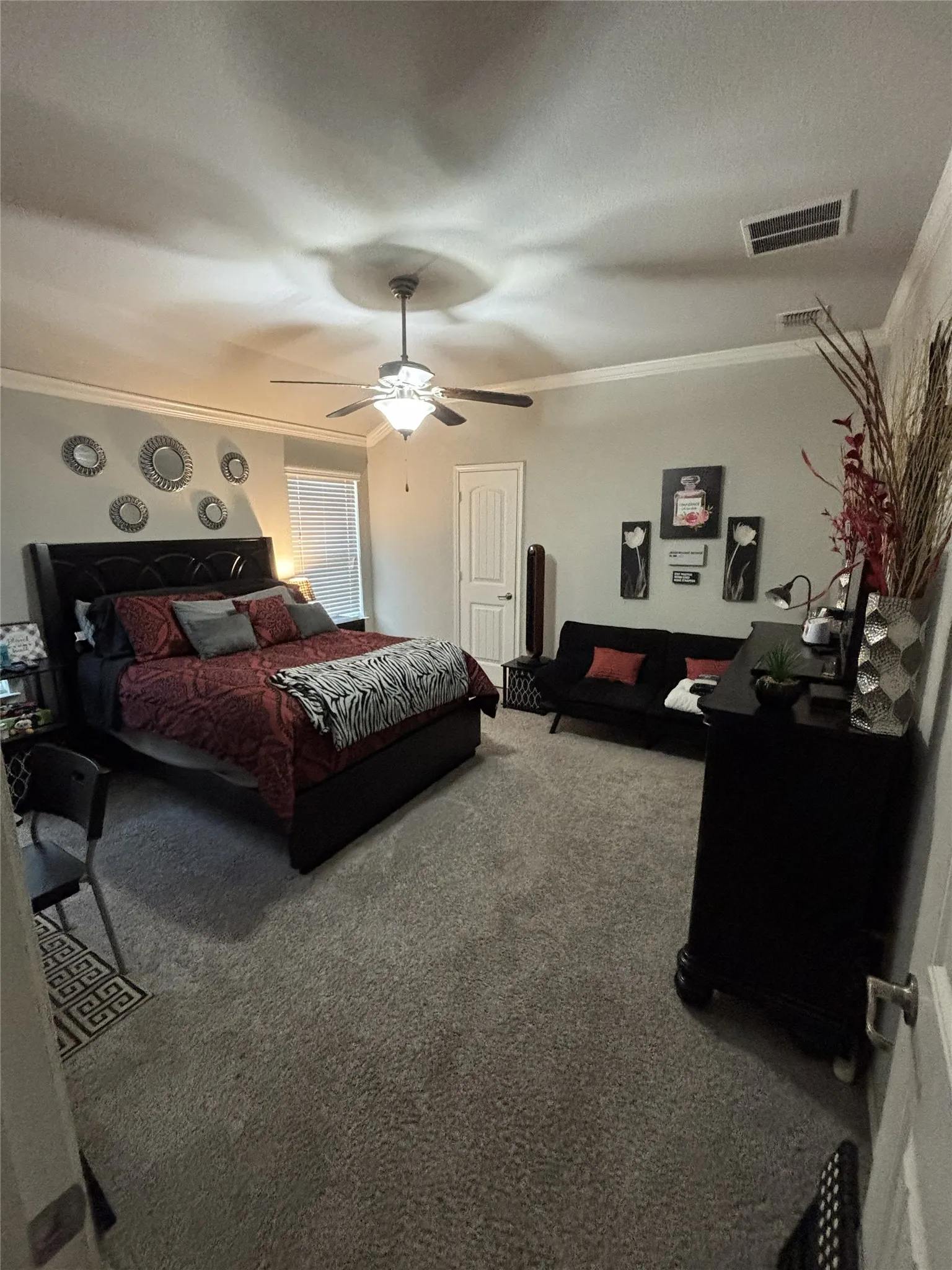 Textured carpeting throughout, crown molding, ceiling fan with integrated lighting, and a white paneled door