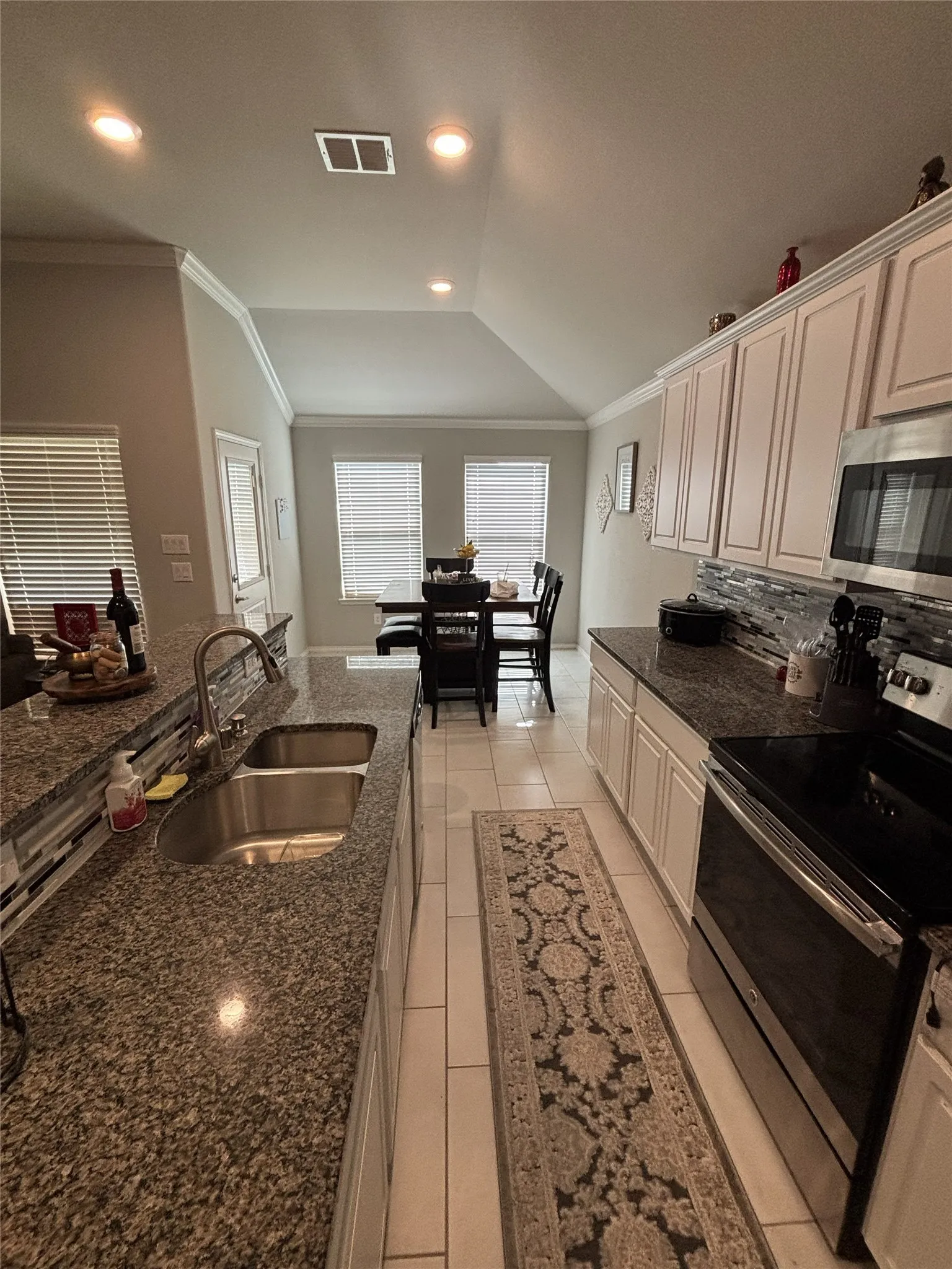 Kitchen featuring granite countertops, a stainless steel double basin sink, white cabinetry, a built-in microwave, and an electric range