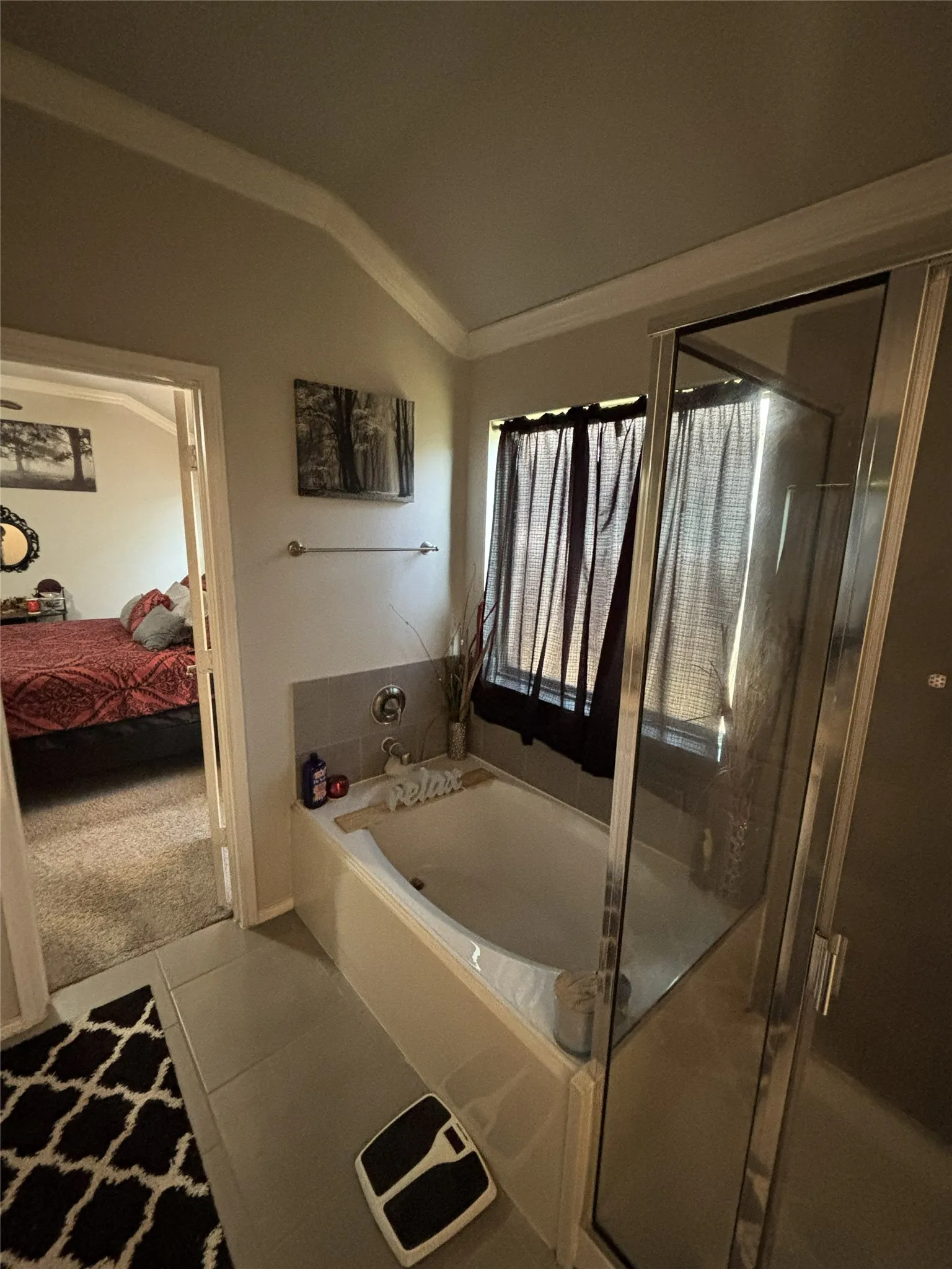 Soaking tub with tile surround, adjacent glass-enclosed shower, and tile flooring