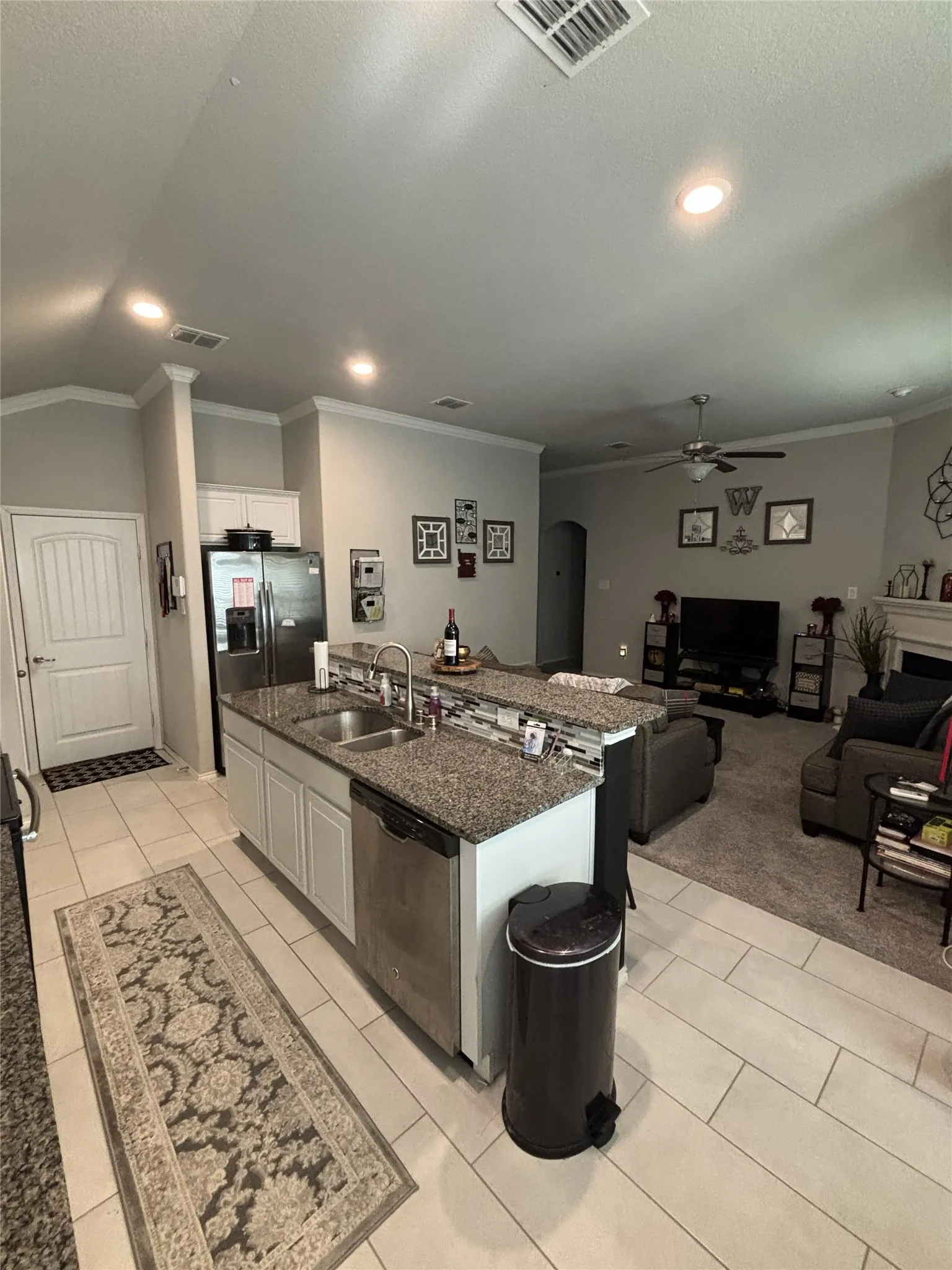 Kitchen island featuring a double-basin sink, stainless steel dishwasher, and granite countertops