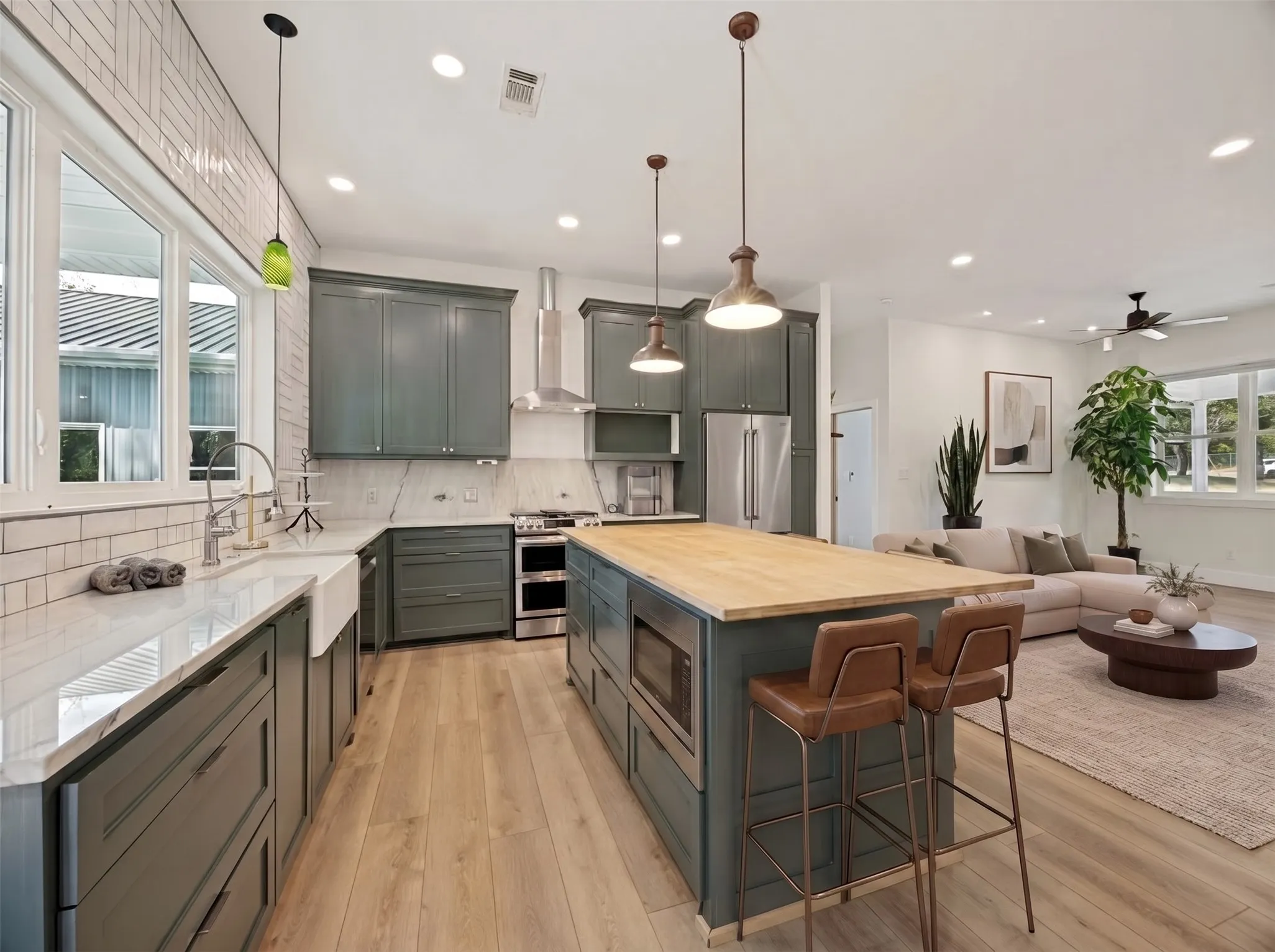 Open-concept kitchen with wood-finish flooring, a large center island, recessed lighting, and stainless steel appliances. This photo has been virtually staged with living room furniture