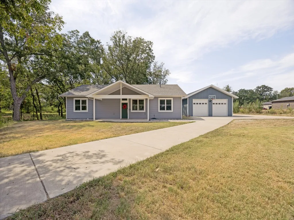 Single-story residence featuring light gray siding, white trim, and a dark green entry door