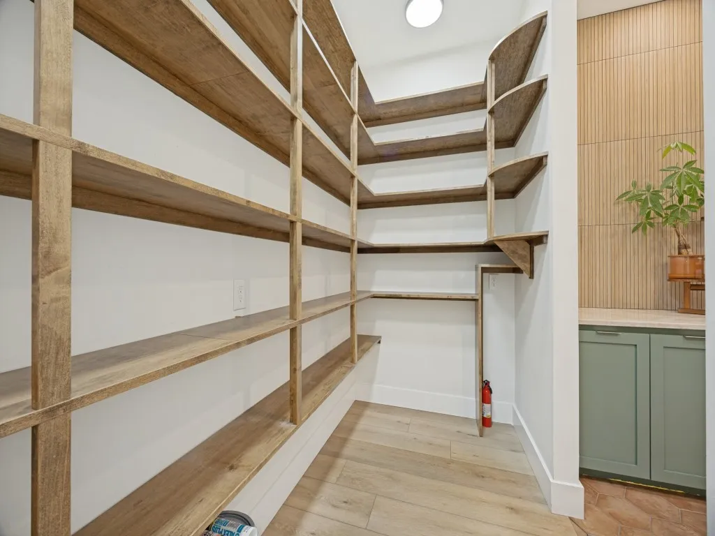 custom walk-in pantry featuring extensive wood-finish shelving and opens into the laundry room