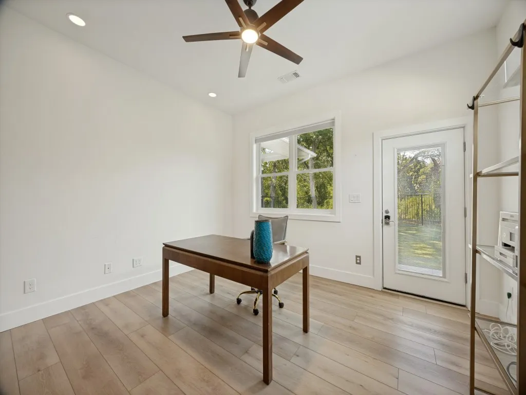 Vaulted ceiling, wood-finish flooring, recessed lighting, ceiling fan, and exterior door with frosted glass panel